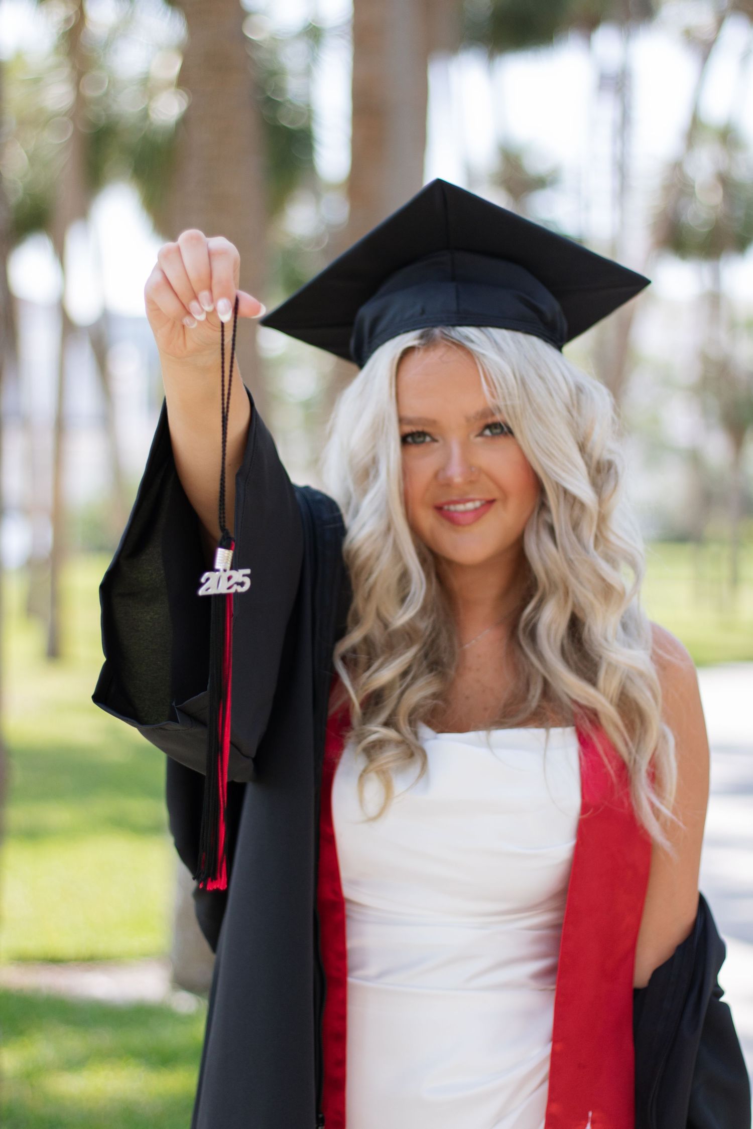 A University of Tampa graduate poses for her grad photos holding her cap cord taken by Tampa grad photographer Michaela Gom Photography.