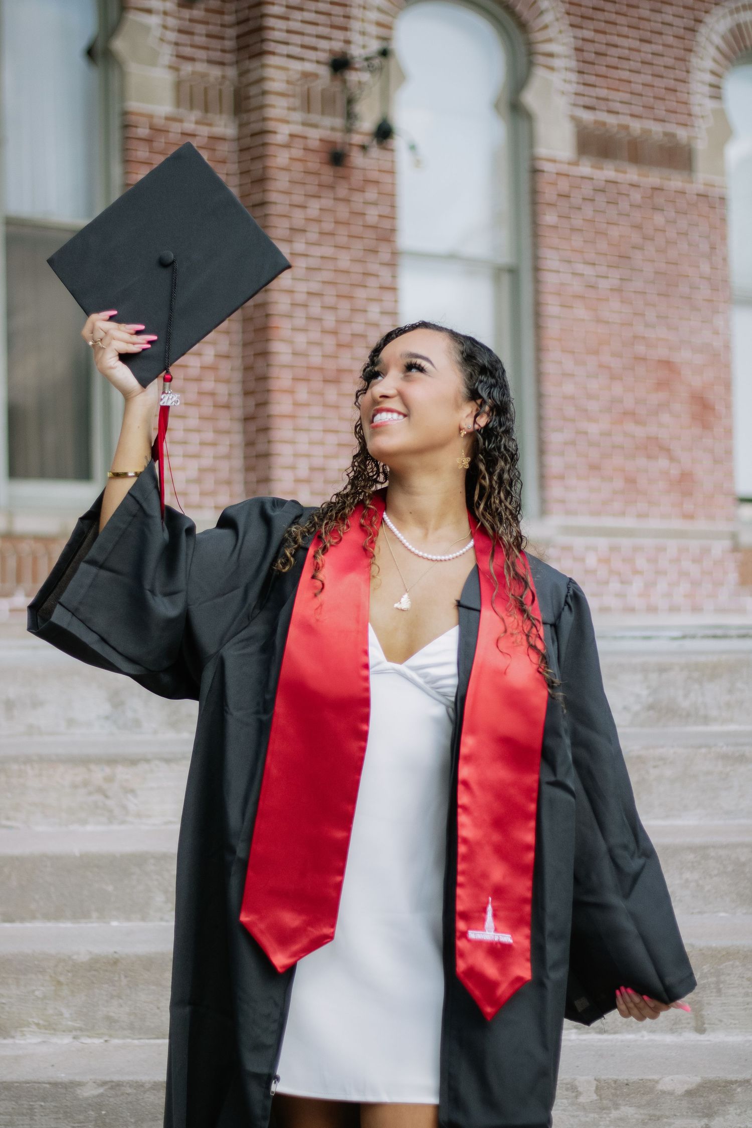 A University of Tampa graduate poses for her grad photos holding up her cap captured by grad photographer Michaela Gom Photography.
