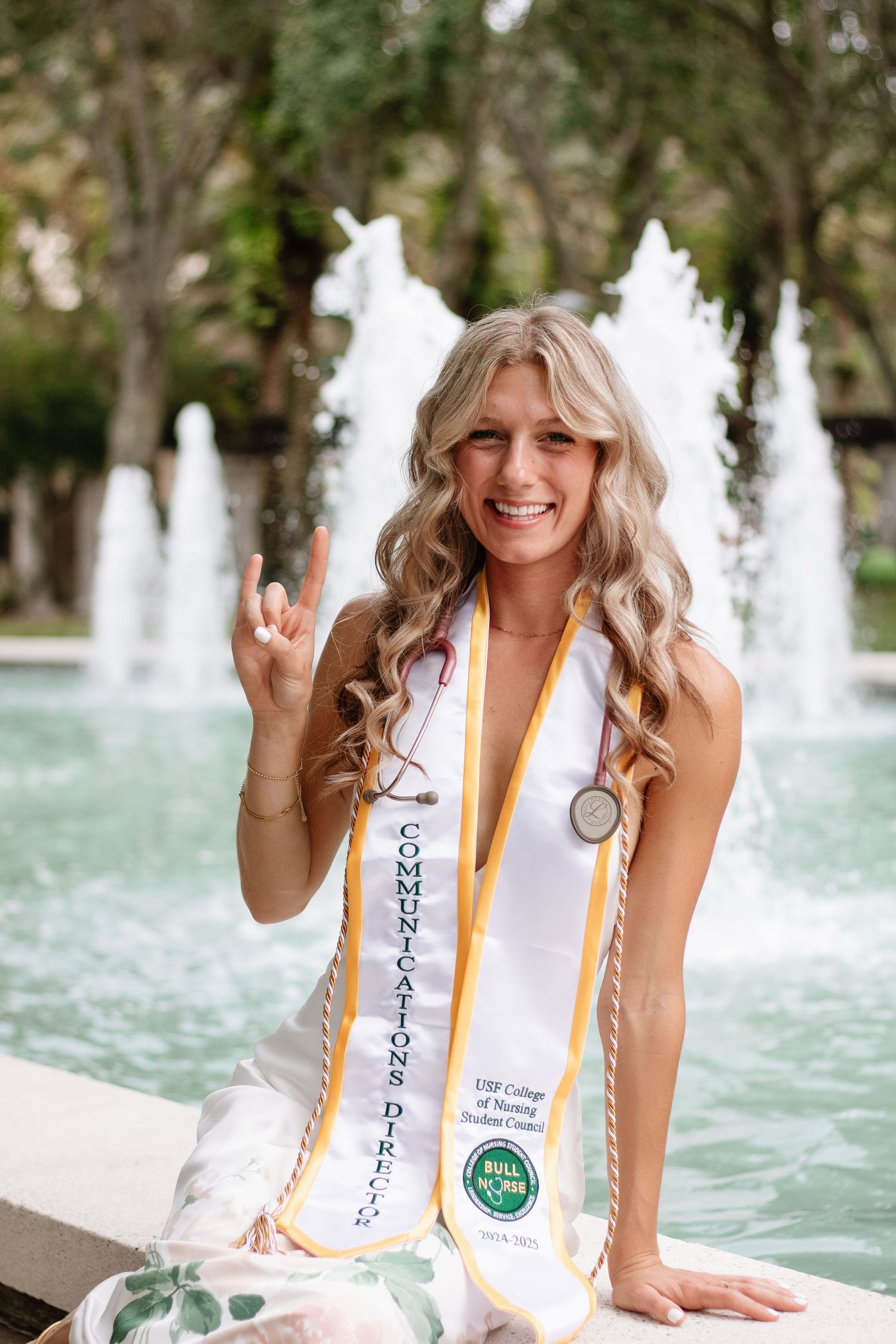 A University of South Florida graduate is sitting on the ledge of the MLK Jr fountain by Tampa grad photographer Michaela Gom Photography.