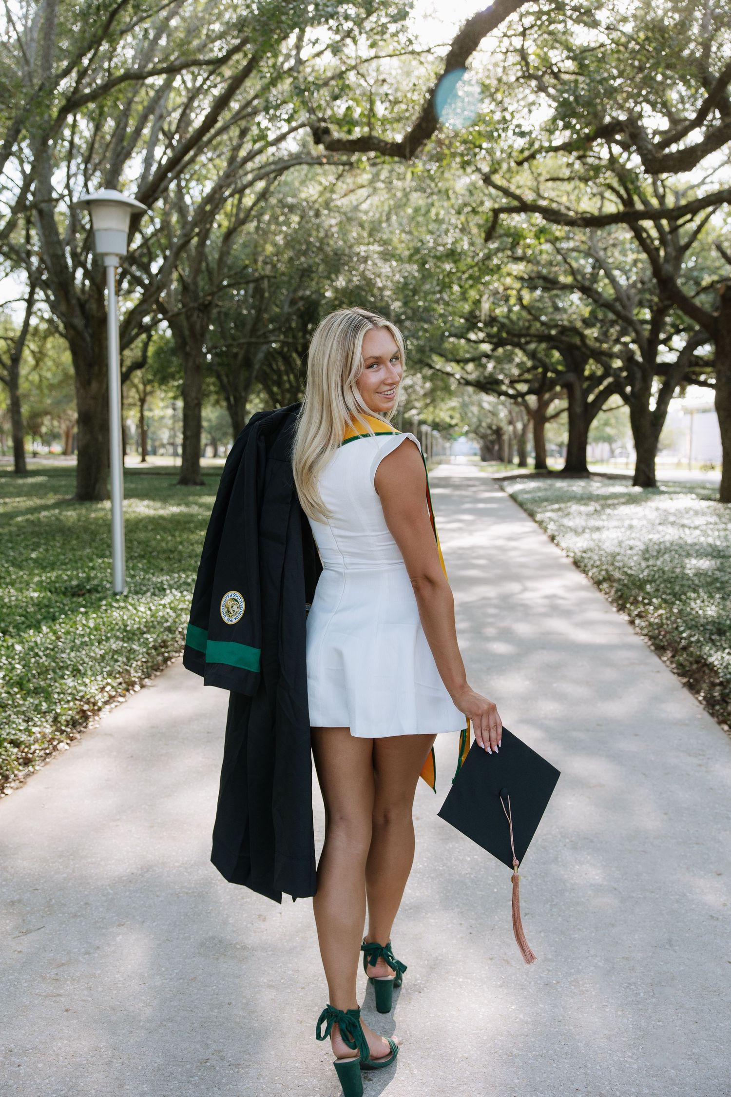 A University of South Florida graduate holds her gown and walks away taken by Tampa grad photographer Michaela Gom Photography.