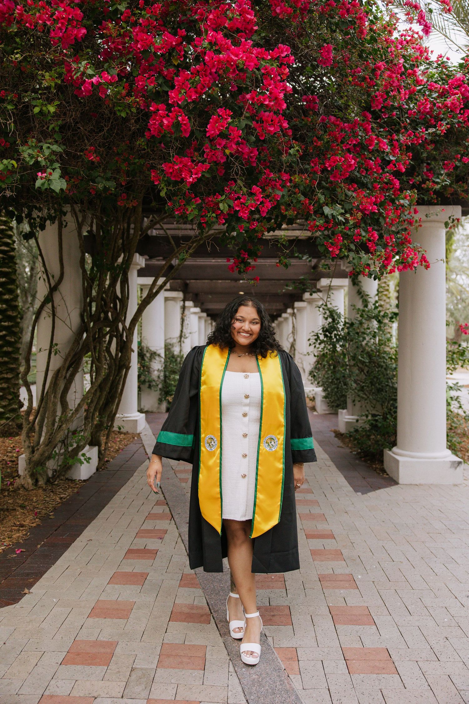 A University of South Florida graduate stands under some flowers taken by Tampa grad photographer Michaela Gom Photography.