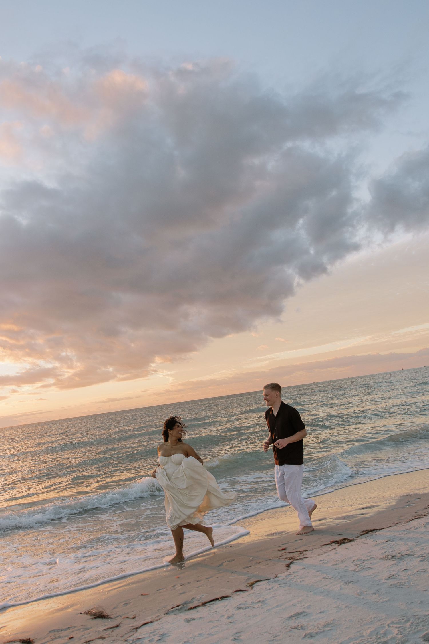 Engaged couple captured running into the sunset at Indian Rocks Beach by Michaela Gom Photography.