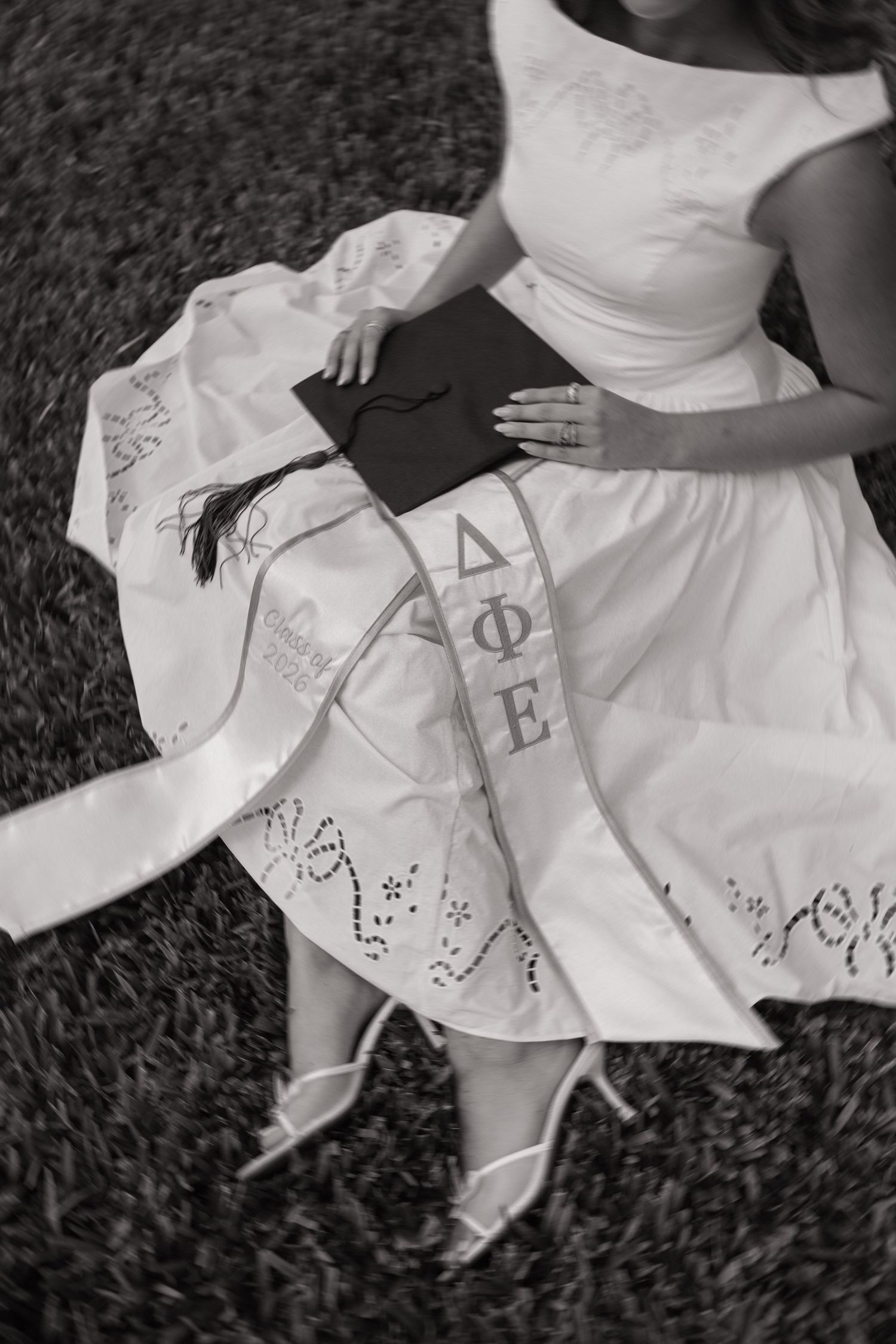 A University of Tampa graduate poses in the grass showing off her sorority stole and cap by photographer Michaela Gom Photography.