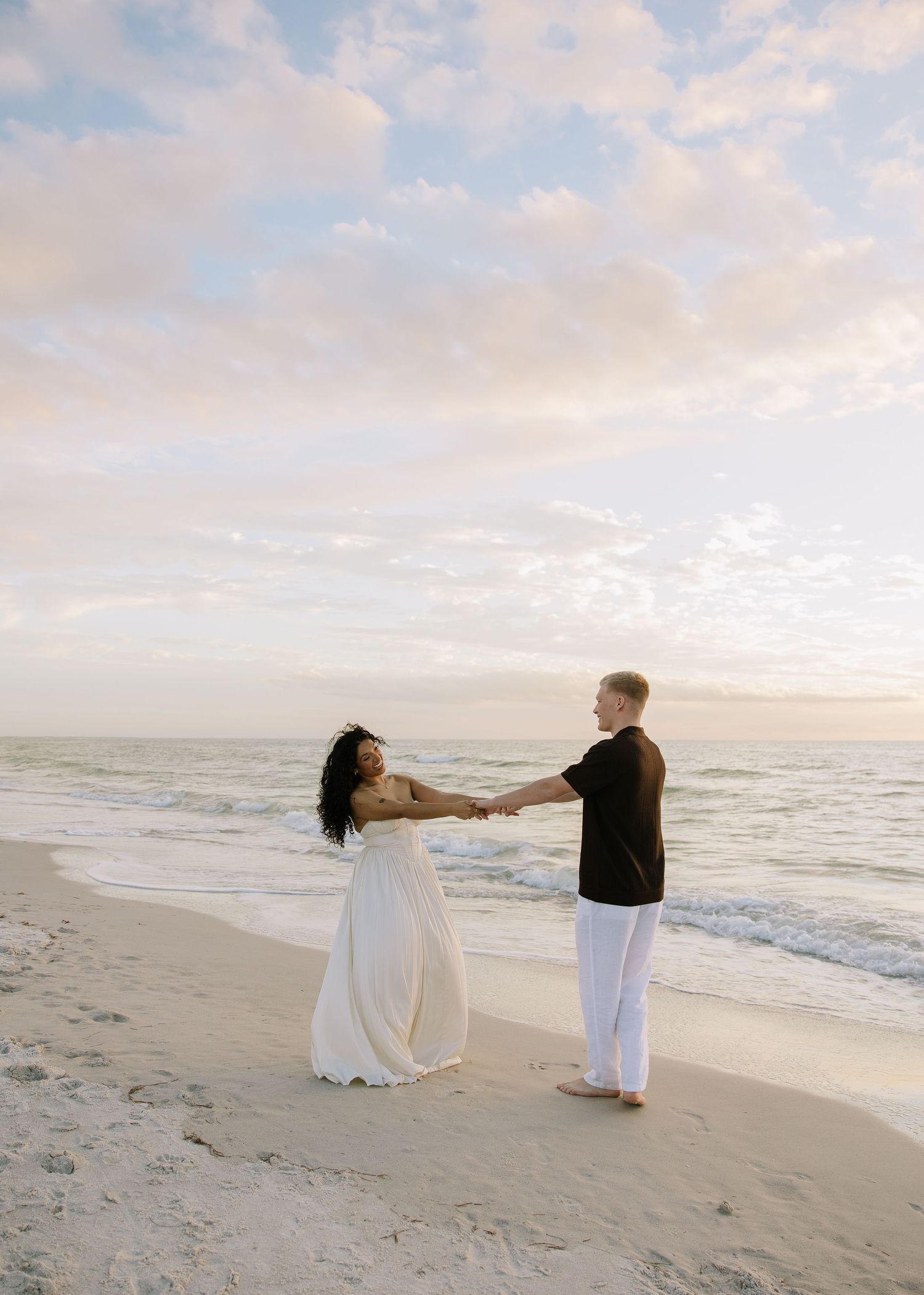 A engaged Tampa couple is dancing on Indian Rocks beach during golden hour captured by Michaela Gom Photography.