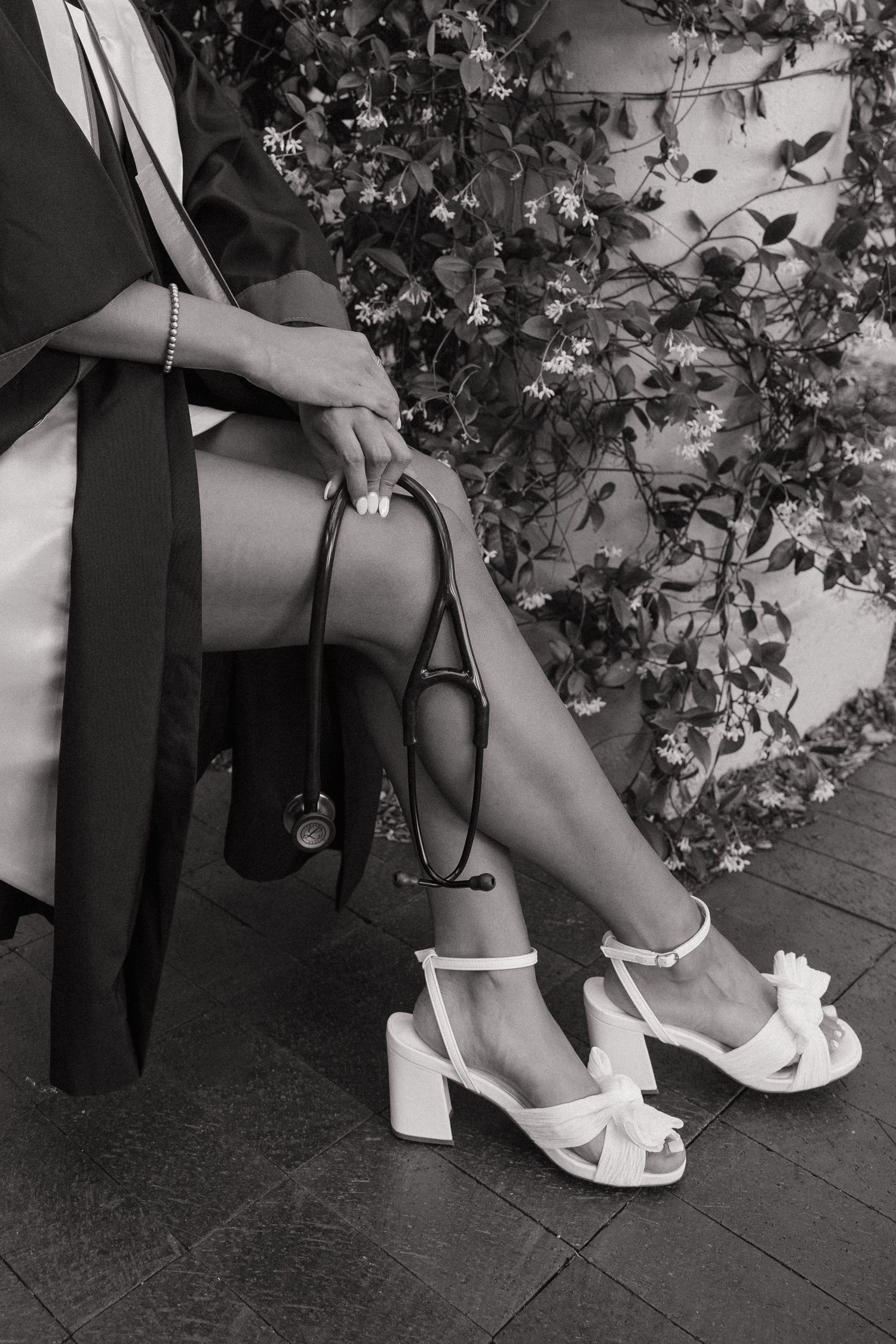 A USF nursing students shows off her heels and stethoscope sitting on a bench for her grad photos captured by Michaela Gom Photography.
