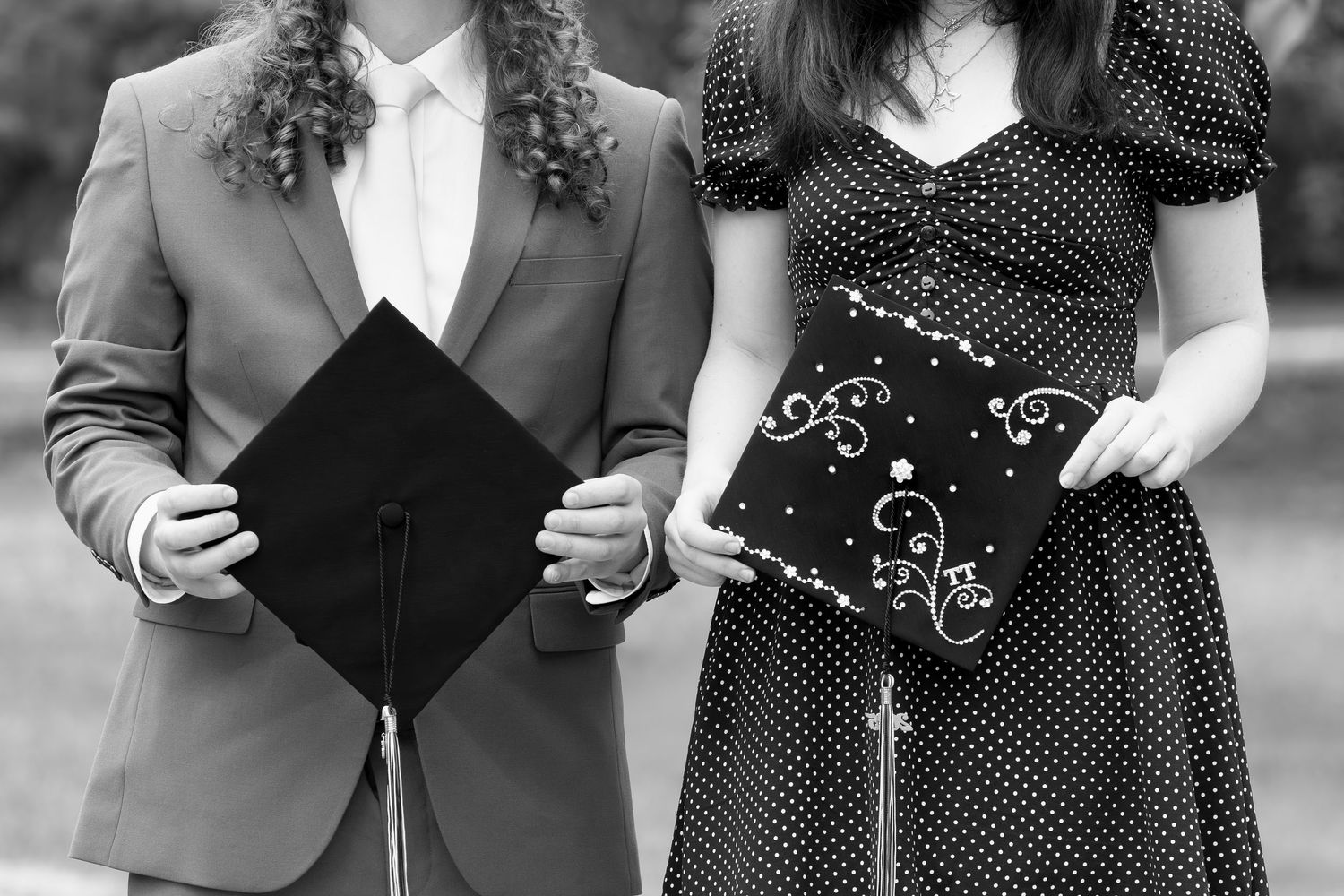 Black and white photo of graduates holding graduation cap and wearing polka dot dress.