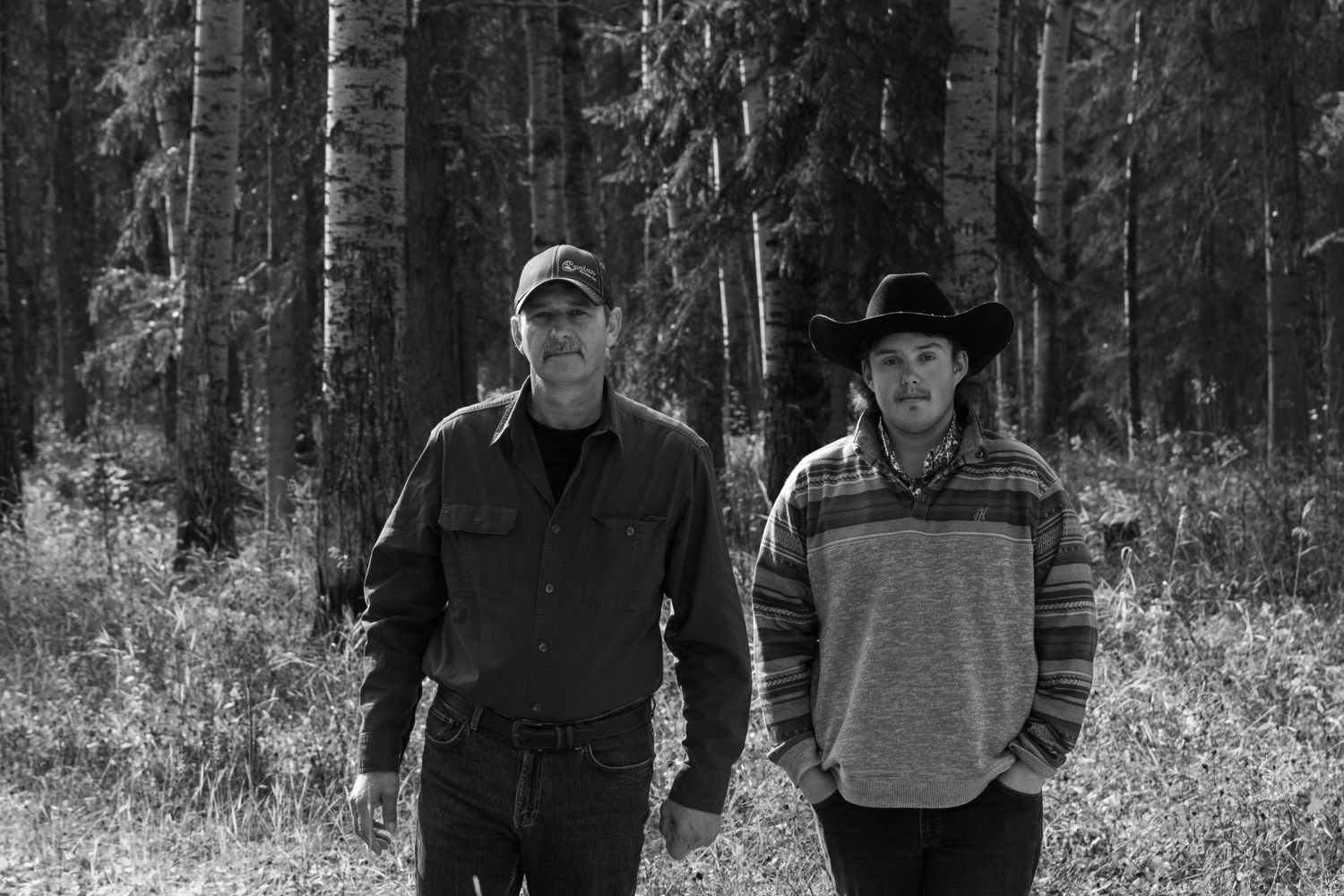 Two people walking together on a forest trail in black and white photography.