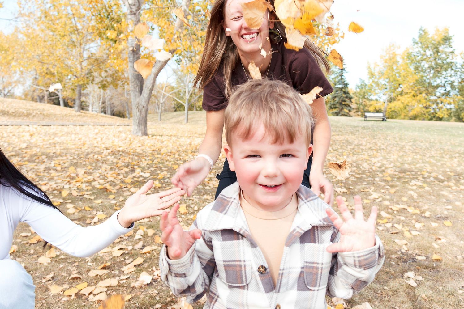 Children playing and throwing autumn leaves in a park during fall season.