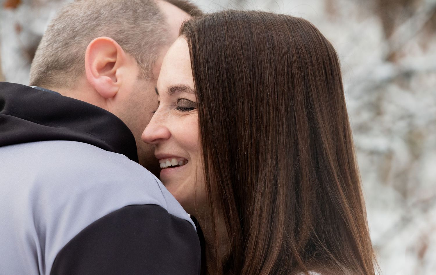 A tender winter moment between two people in a snowy setting.