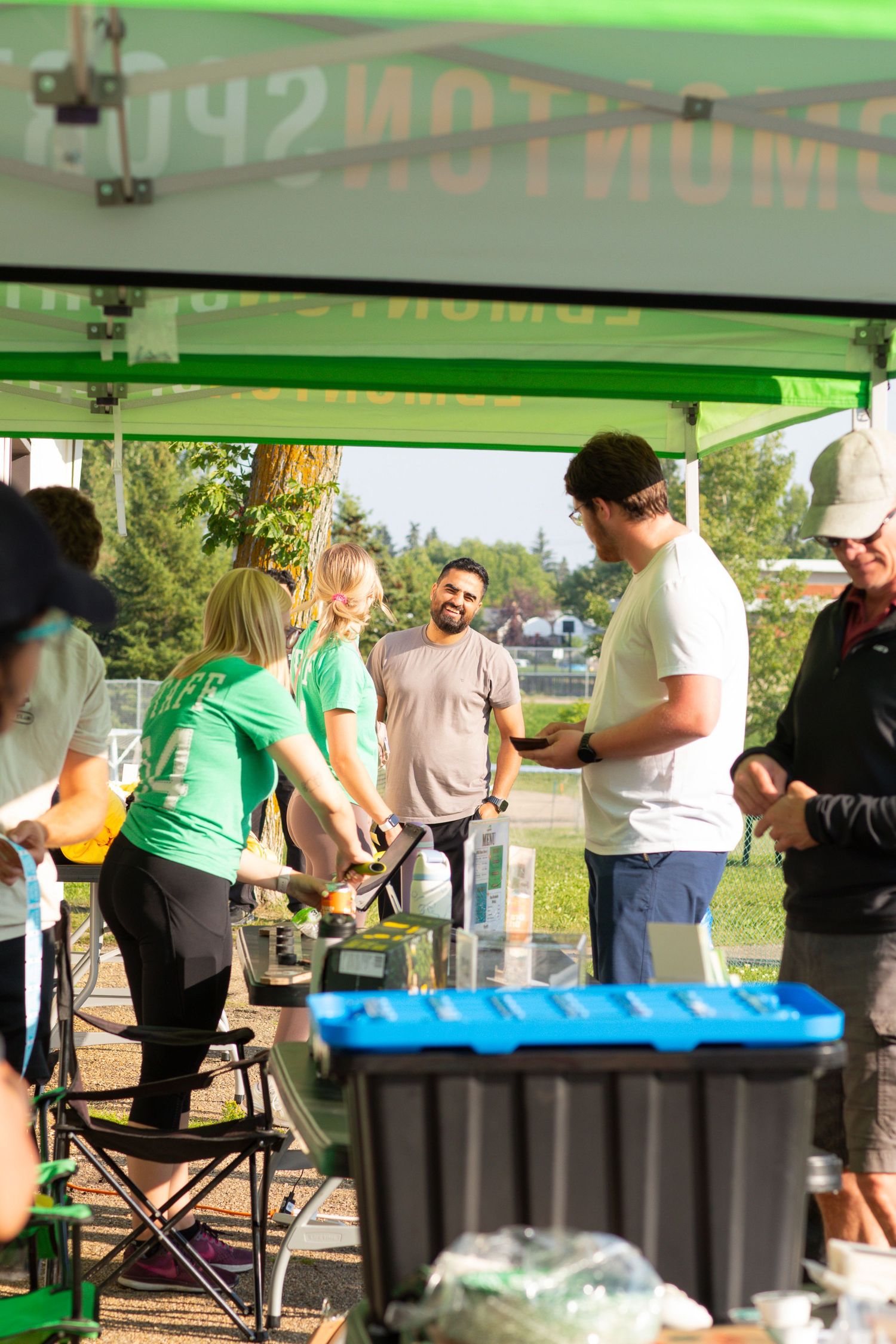 Green canopy tent setup with registration tables and volunteers at outdoor event.