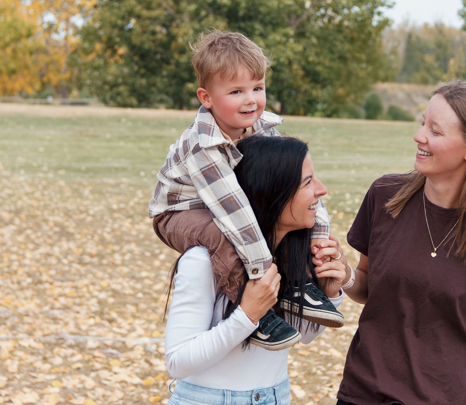 Couple laughing together while holding money outdoors in autumn with fallen leaves scattered on the ground.