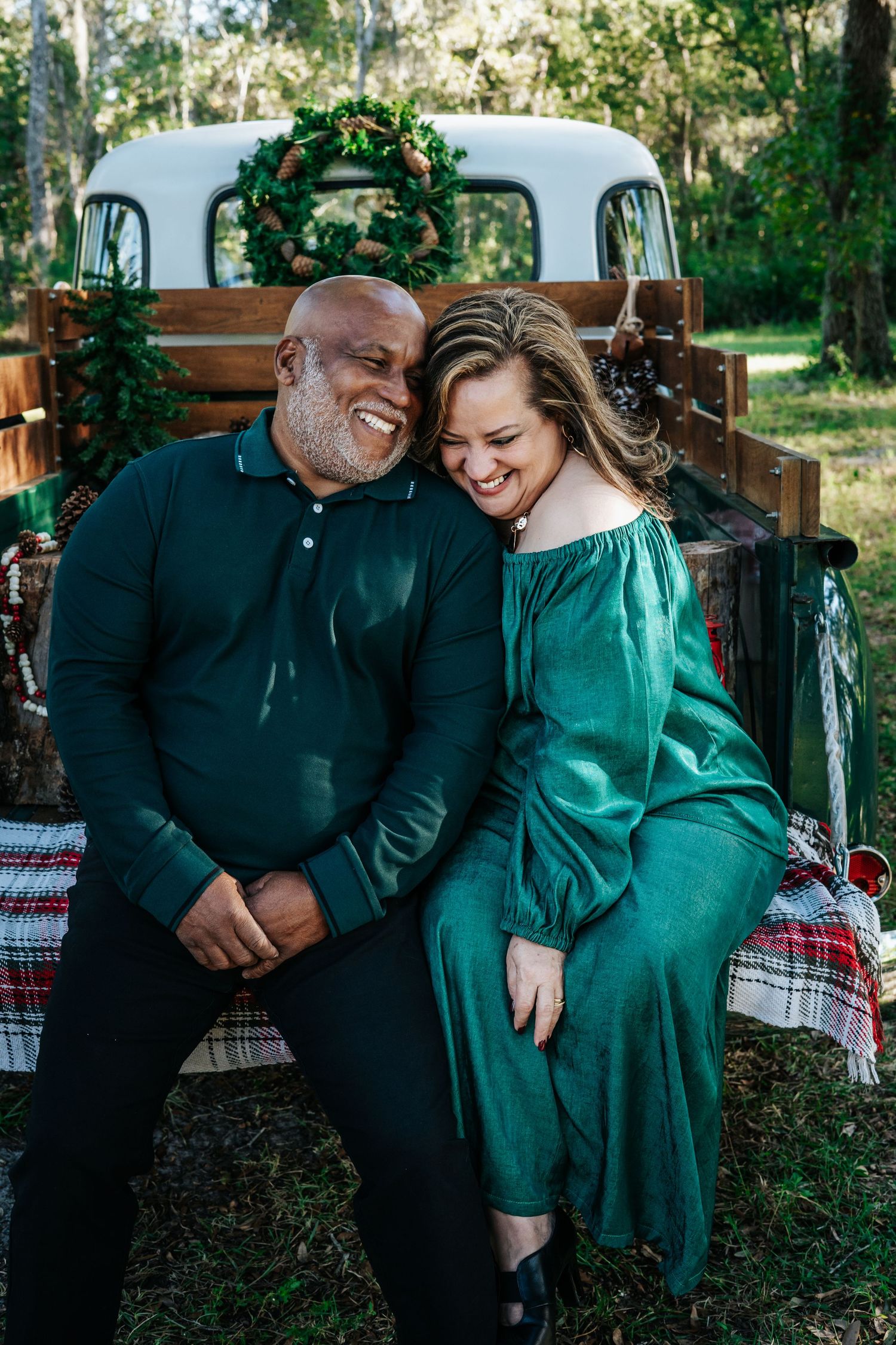 Couple in green and black outfits sharing intimate moment on outdoor bench.