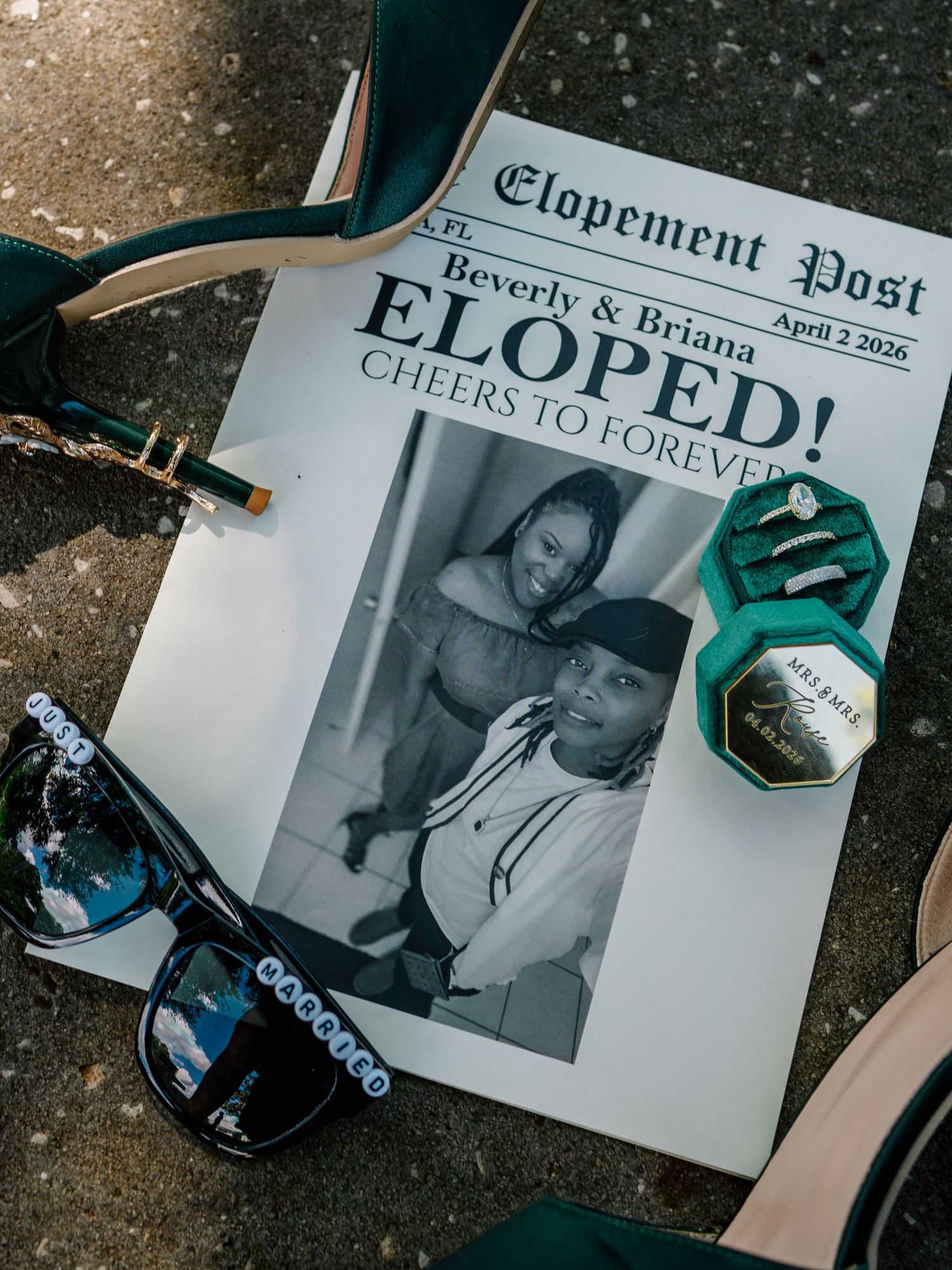 Elopement announcement newspaper prop with couple photo, ring box, sunglasses, and green heels for Beverly and Briana April 2026.