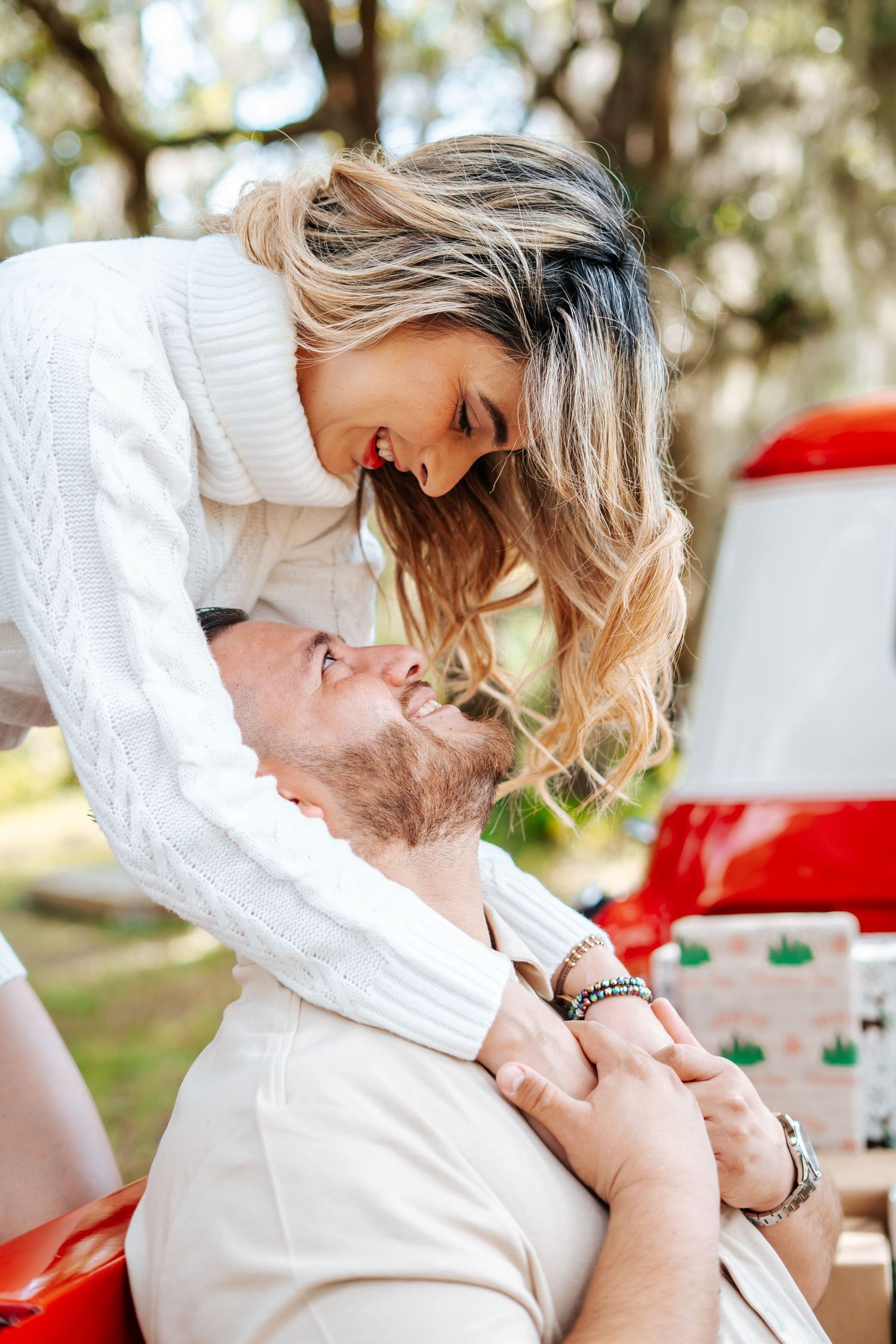 A couple shares an intimate moment outdoors with natural lighting and white clothing.