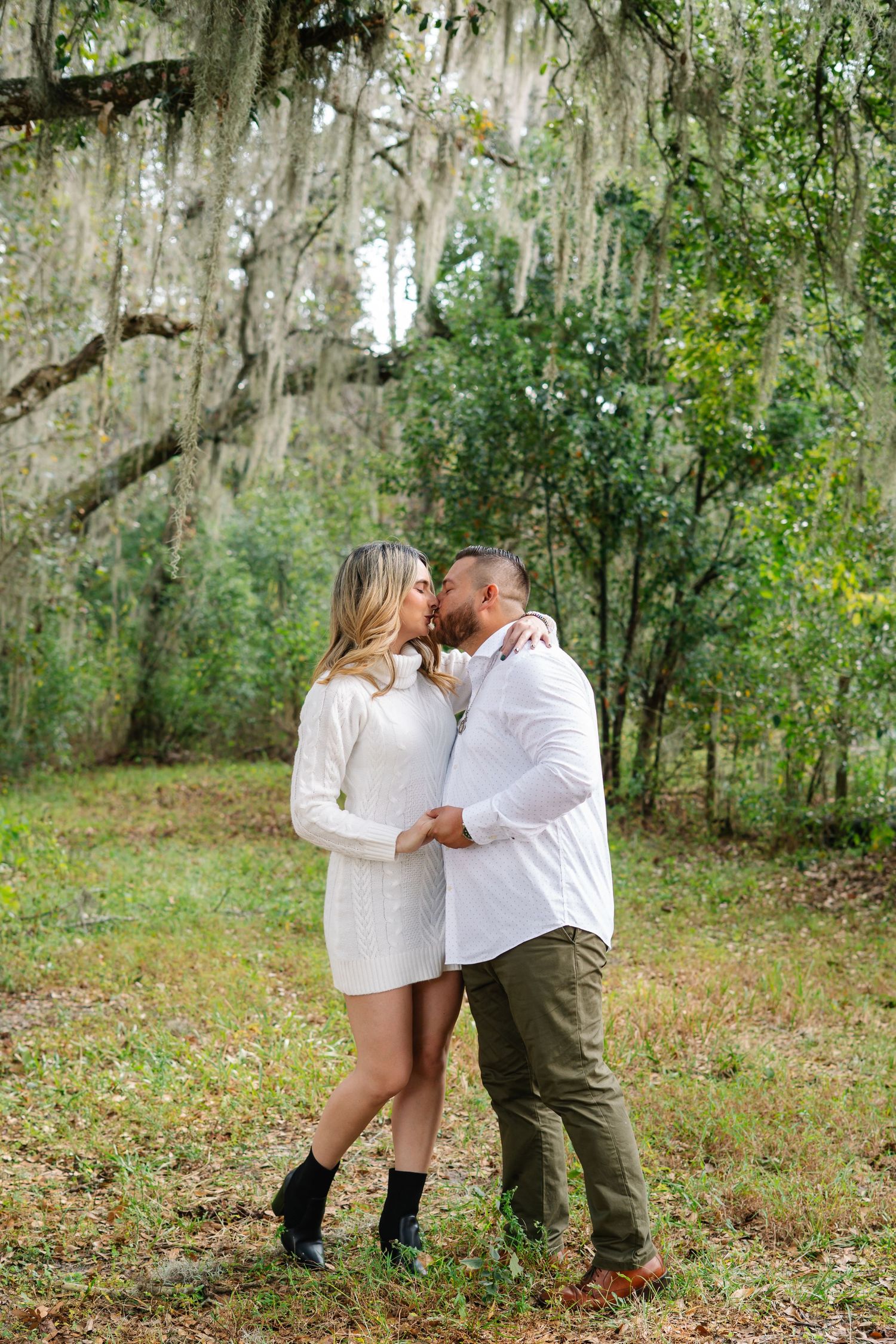 A couple shares intimate moments in a wooded outdoor setting.
