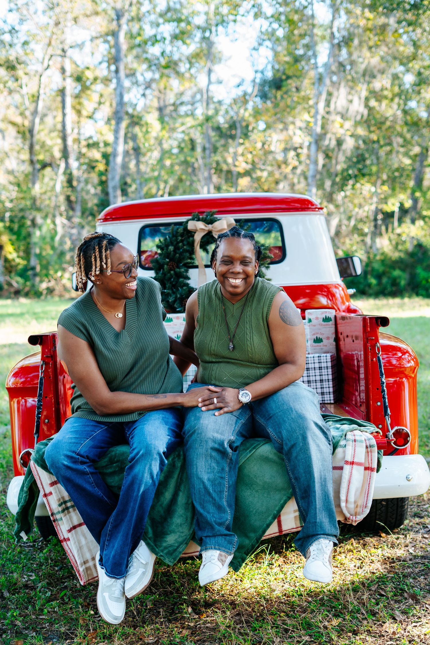 A couple sits together and laughs on the tailgate of a red pickup truck.