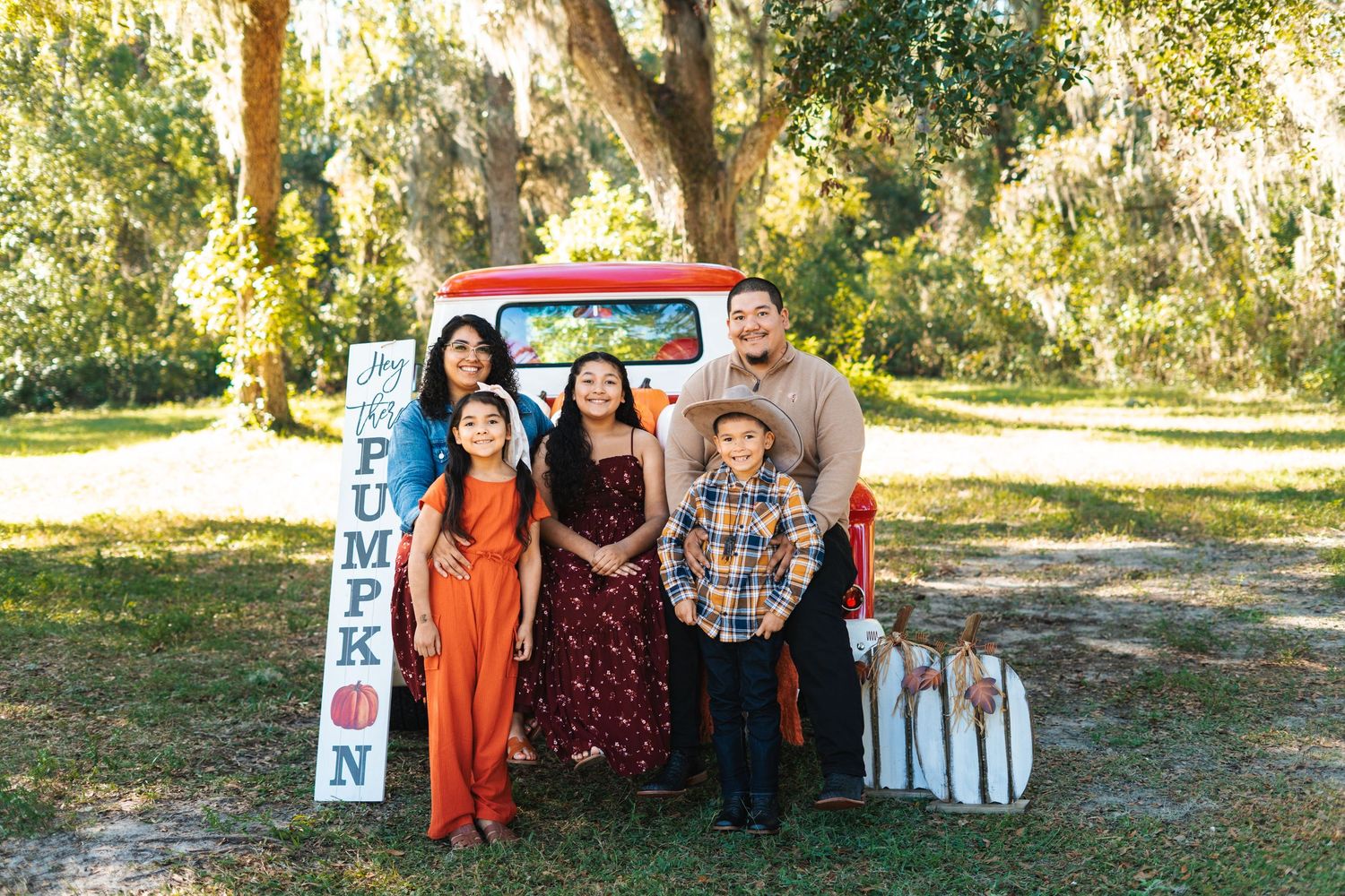 Holiday family portrait session with vintage truck and festive decorations in outdoor setting.