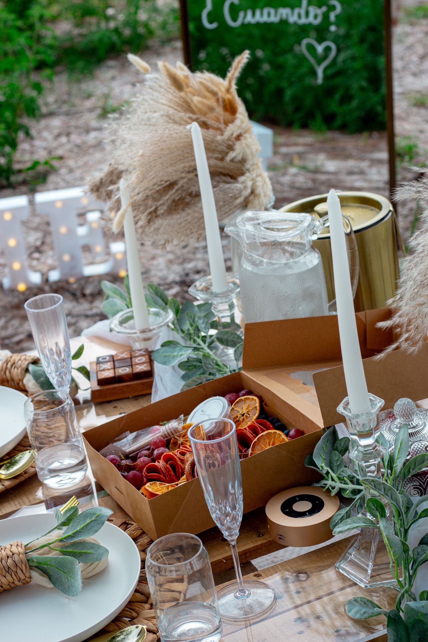 An elegant table setting with candles, glassware and greenery for a romantic outdoor dinner.