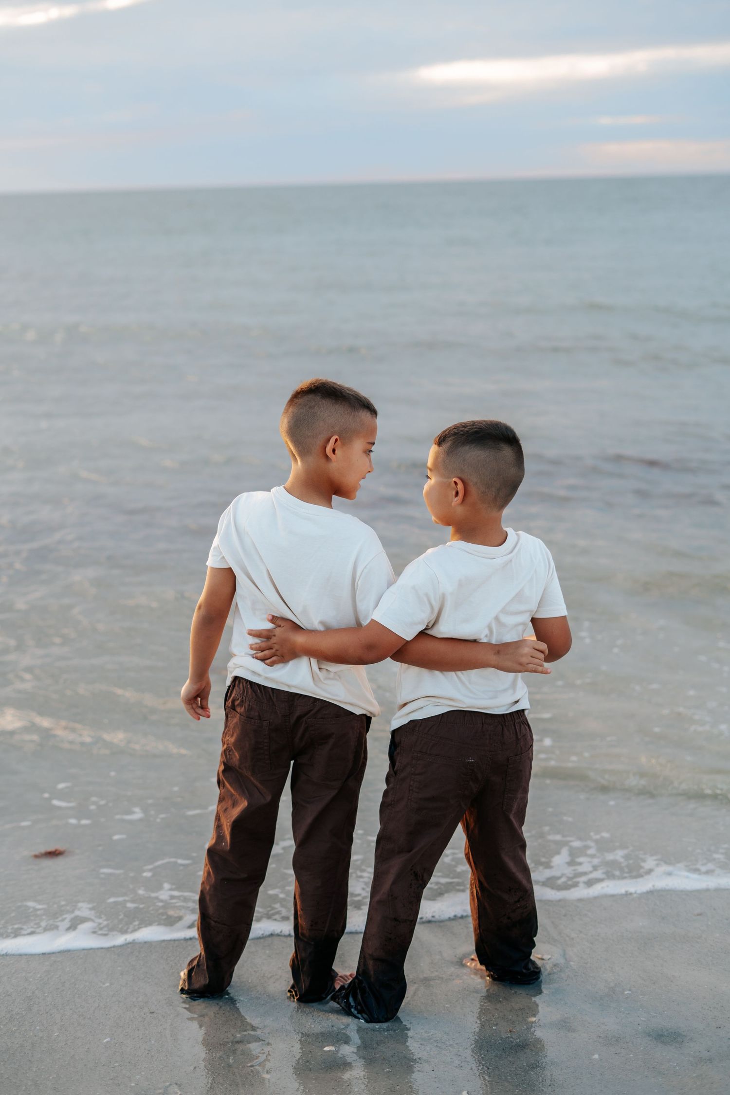 Two children walk together along the shoreline at sunset, creating lasting memories.