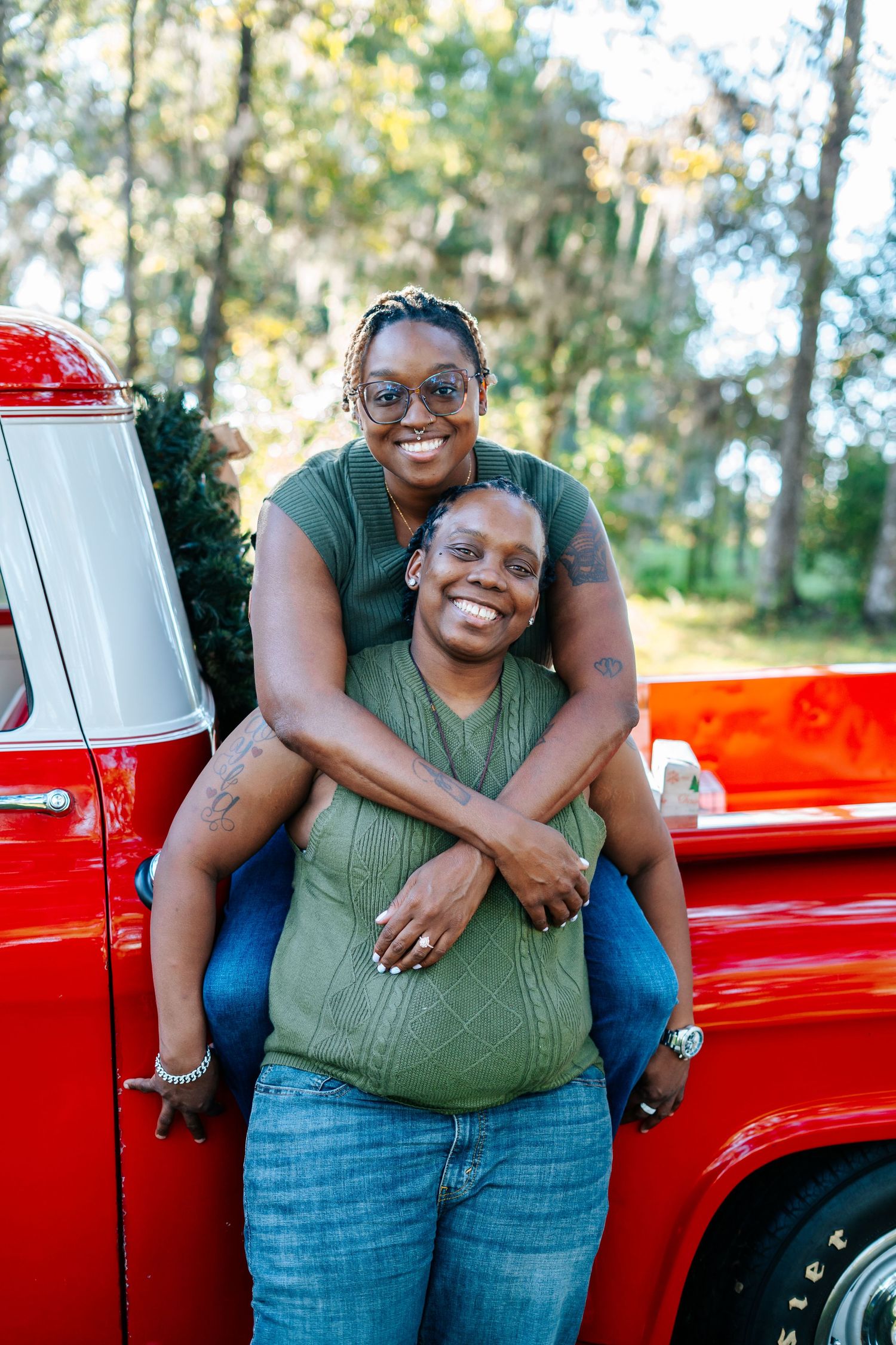 A happy couple poses together against a bright red vintage truck.