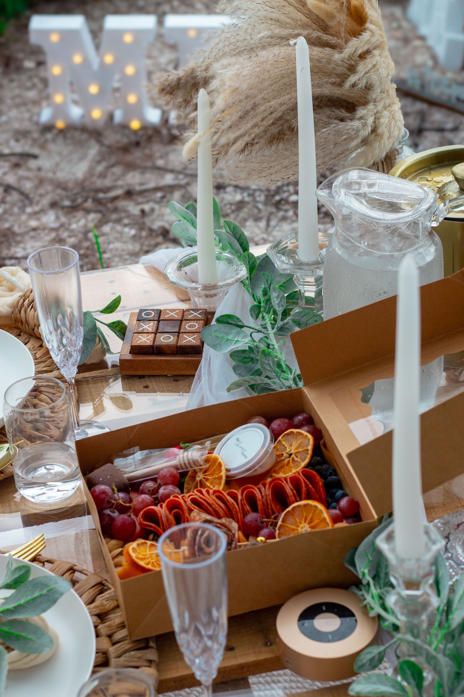 Elegant table setting with candles, dried flowers and glassware for outdoor dining.