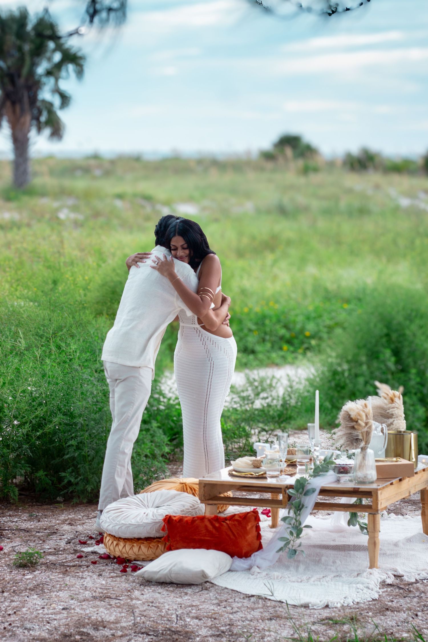 Intimate picnic scene with elegant table setting and white decor in natural setting.