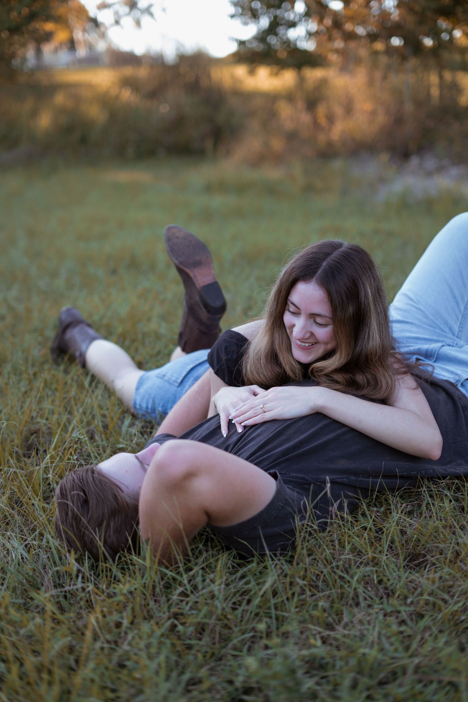 A couple lying together in grass during sunset.