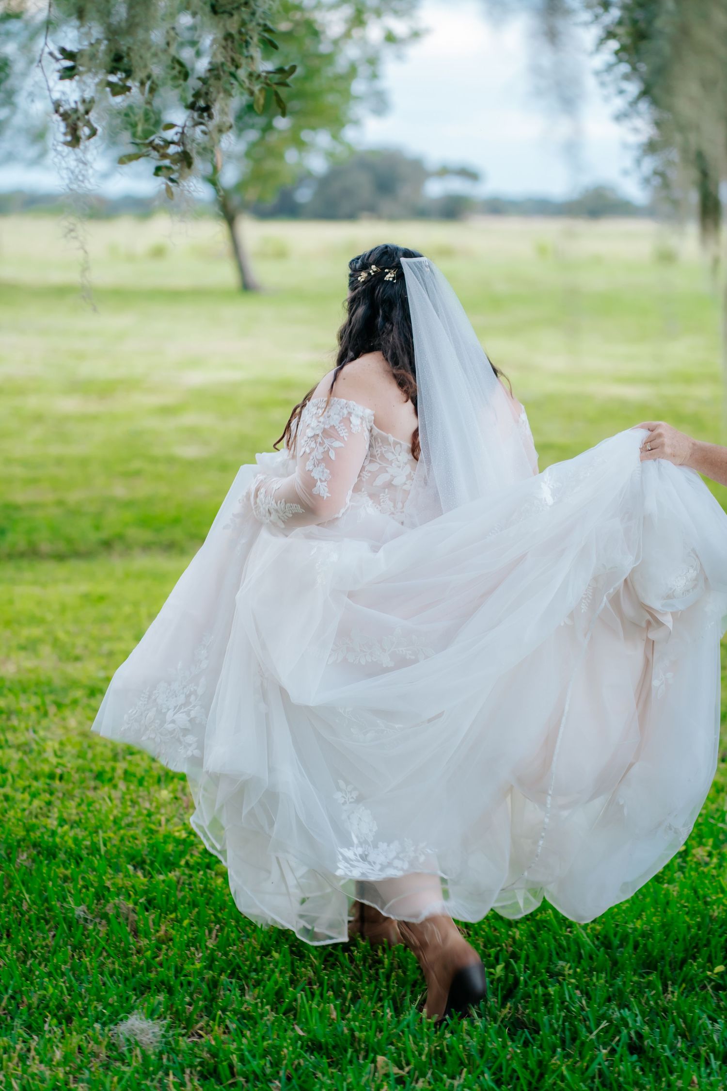 Flowing white wedding dress twirling gracefully on green grass in a garden setting.