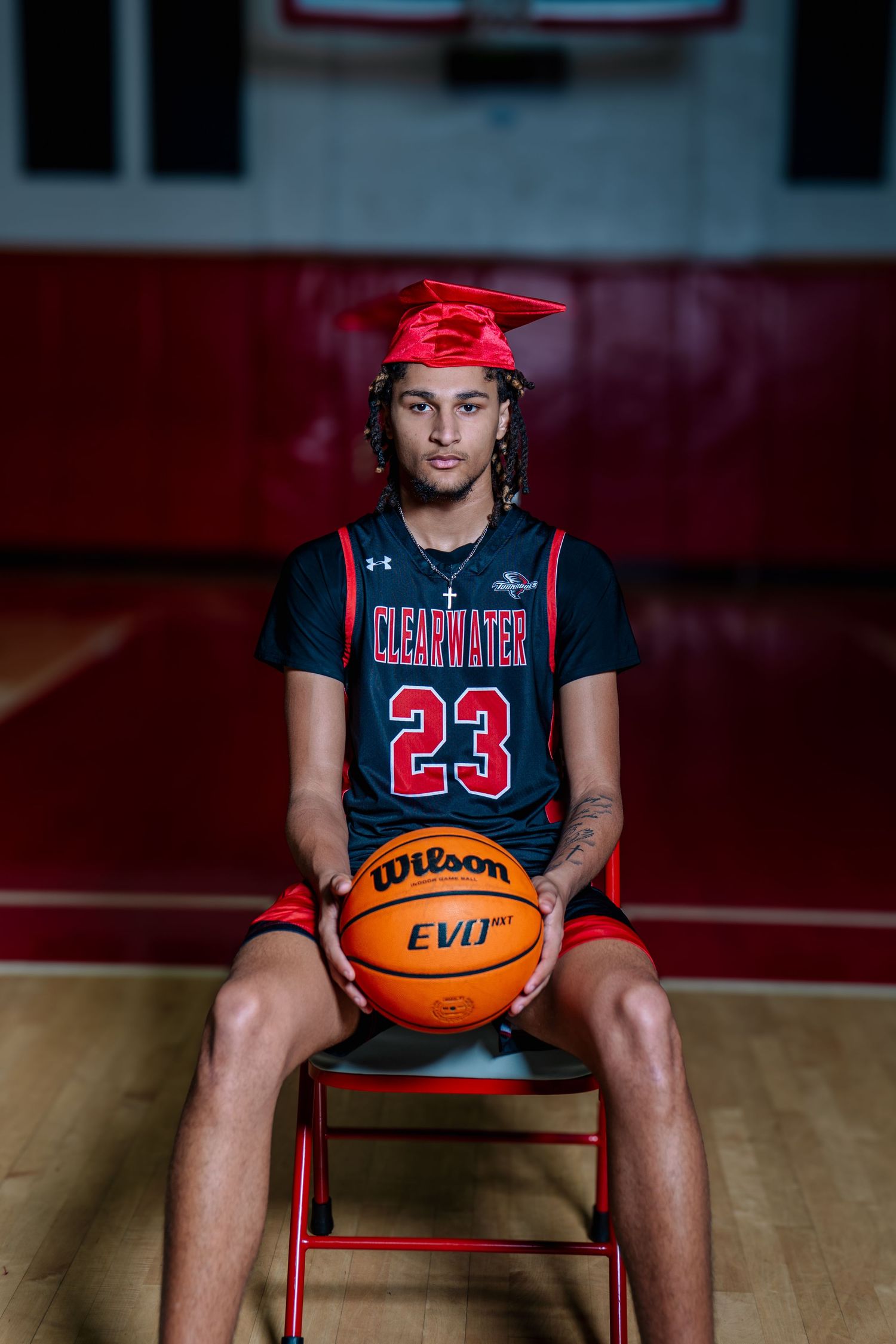 Clearwater #23 basketball player in graduation cap holds Wilson EVO NXT ball on court.