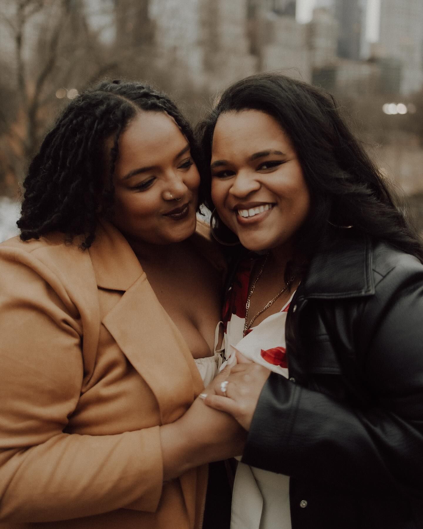 Two friends share an intimate moment of laughter and joy during a winter photoshoot.