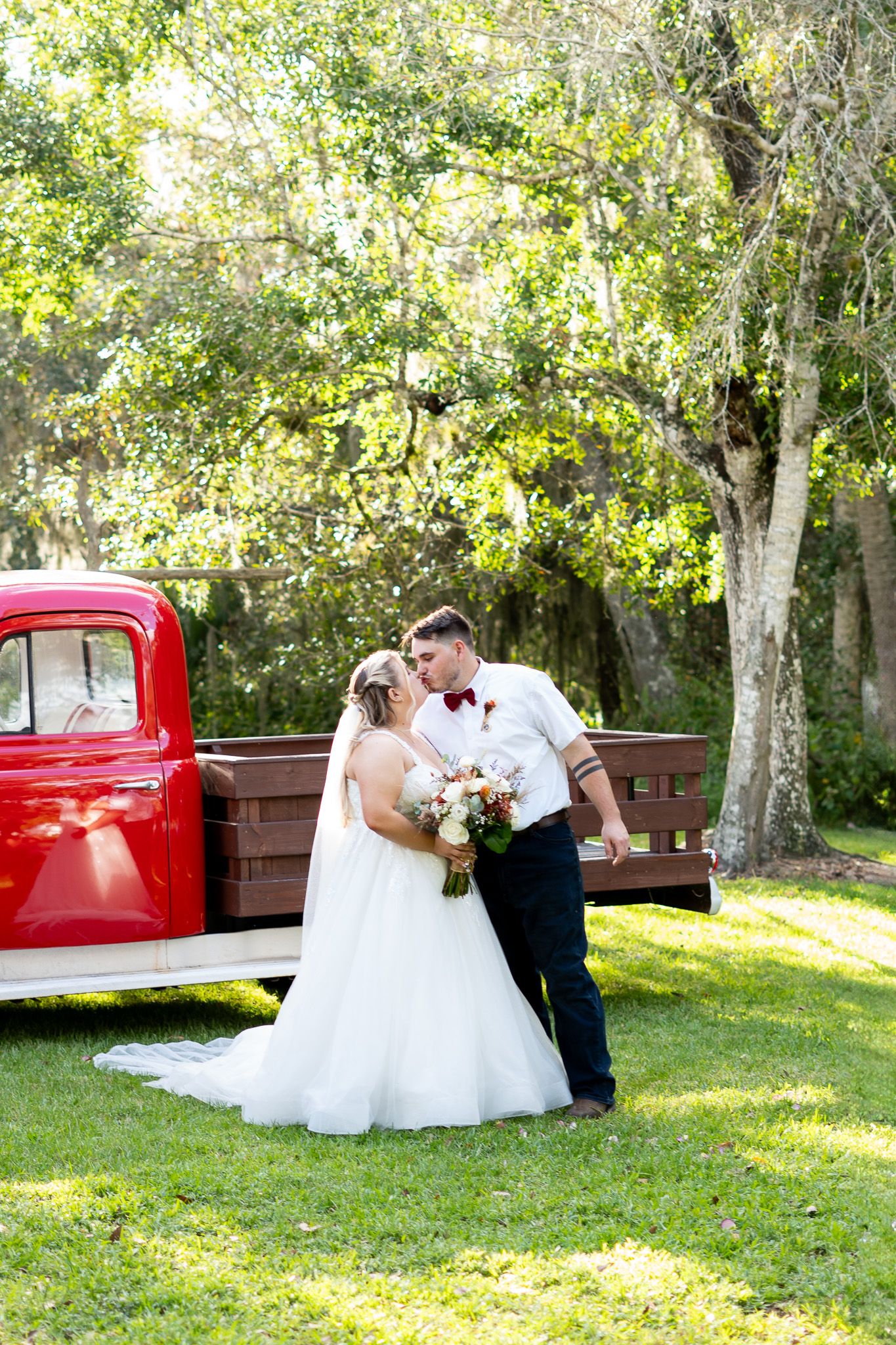 A romantic outdoor photo sequence with a vintage red pickup truck and couple in formal attire on a sunny lawn.