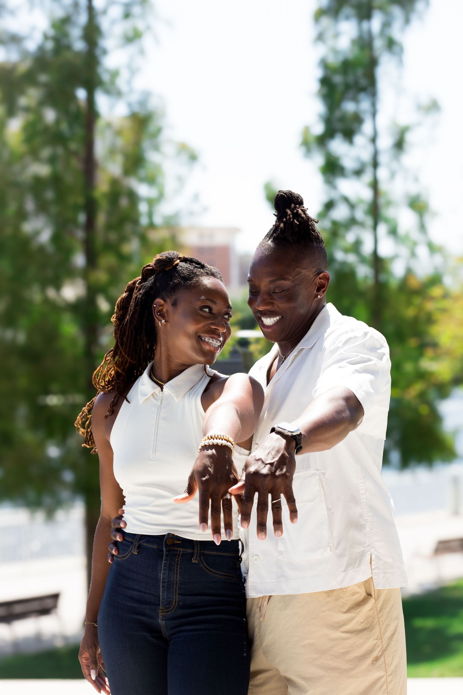 A couple in matching white outfits share a joyful moment together outdoors.