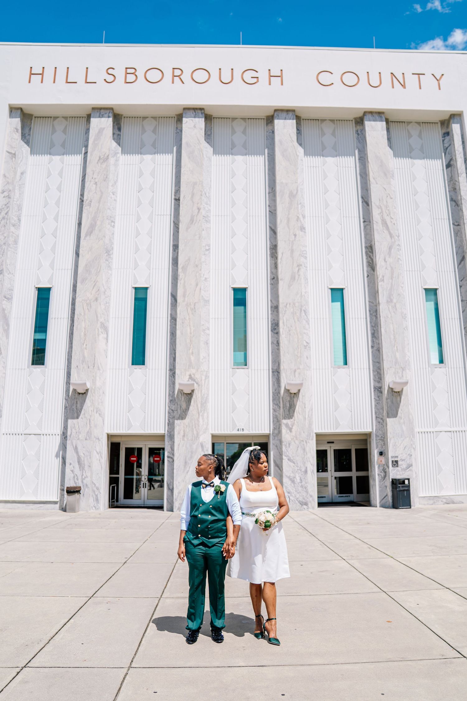 Newlywed couple posing in front of Hillsborough County building on their wedding day in Tampa, FL.