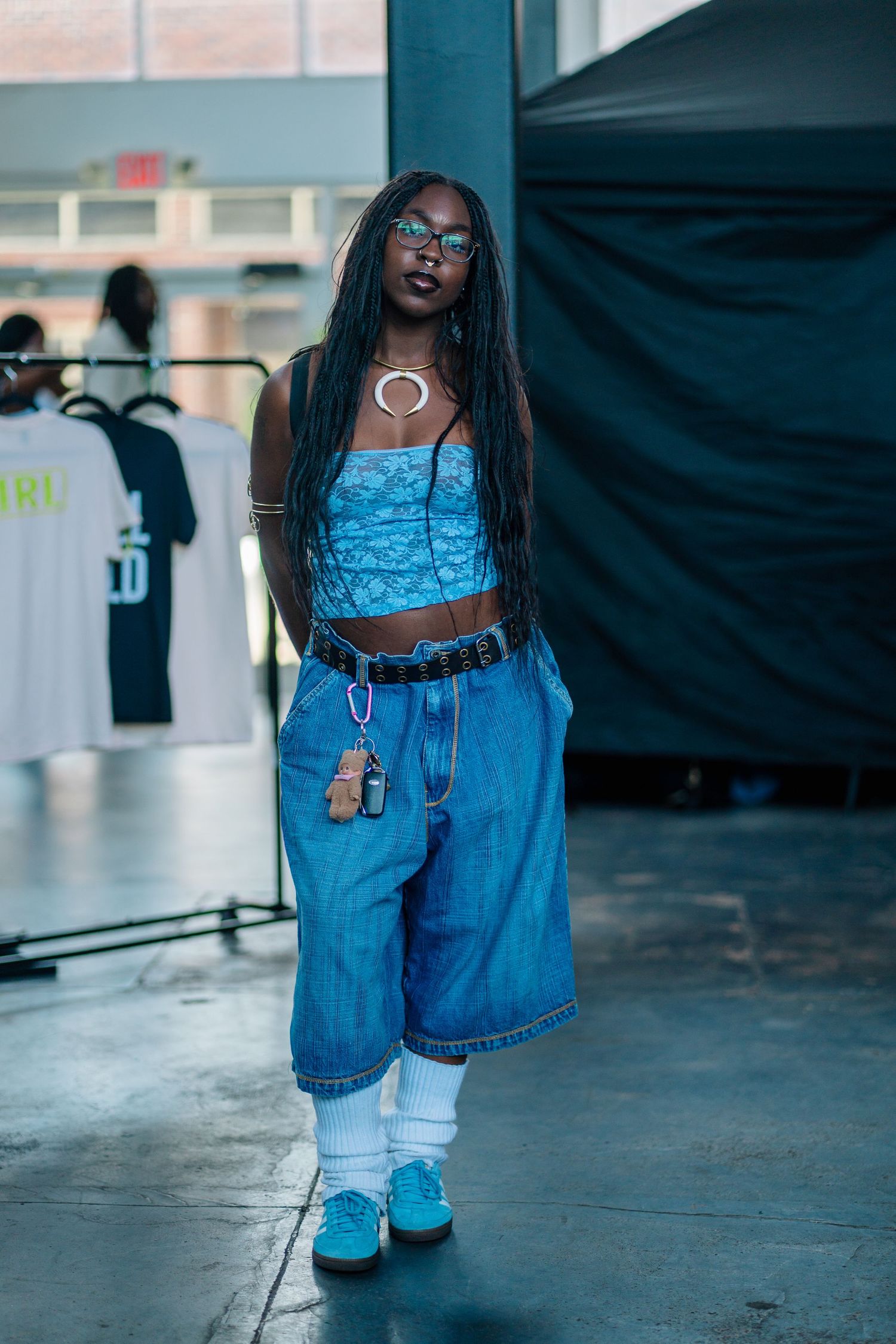 Model in blue denim outfit with crop top and wide-leg shorts at fashion show.