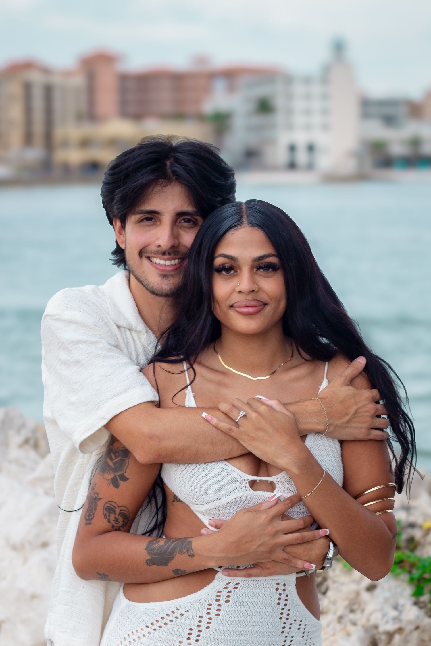 Romantic waterfront couple photos with white outfits against ocean backdrop.