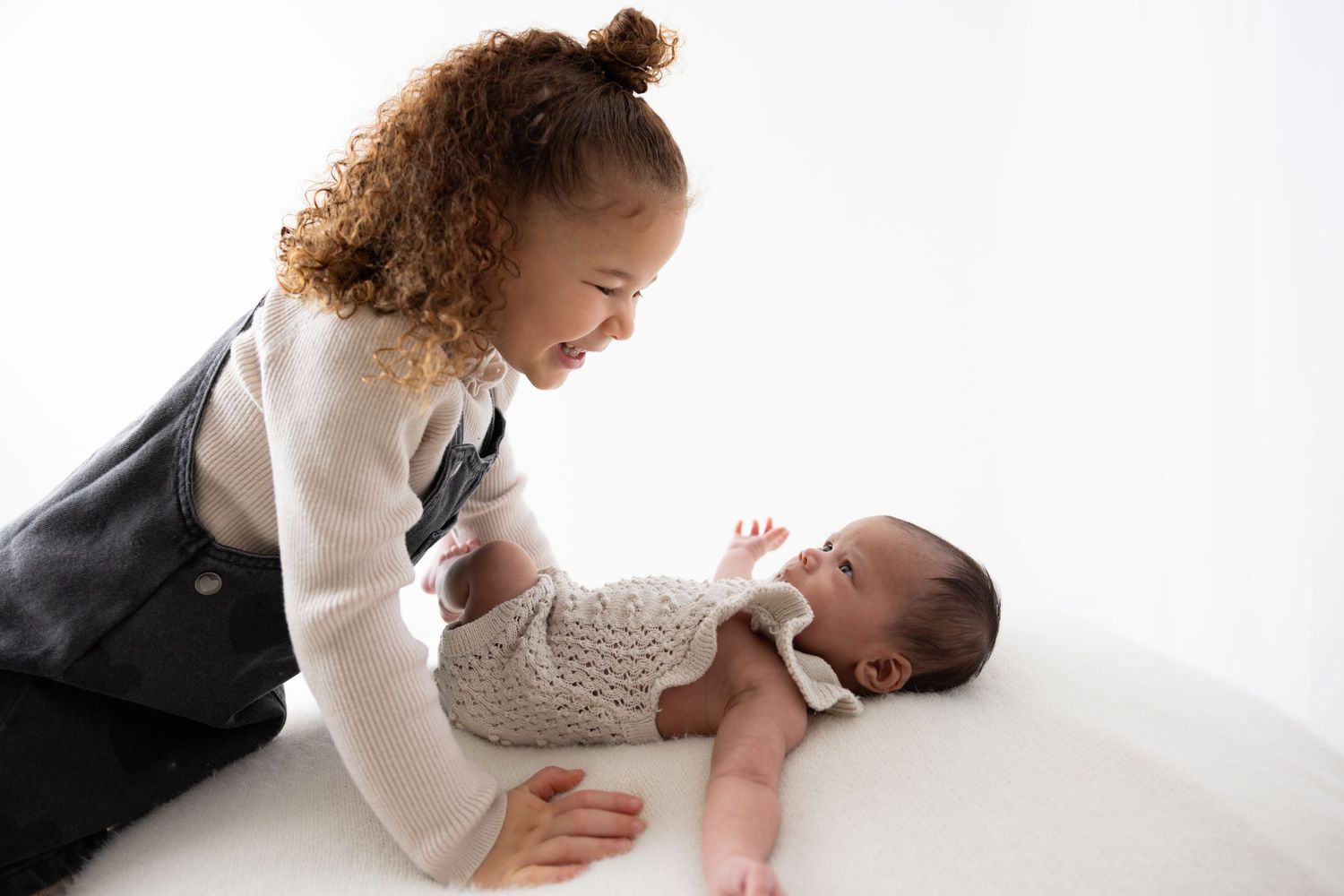 A parent and baby share tender moments together on a white background in a series of candid photographs.