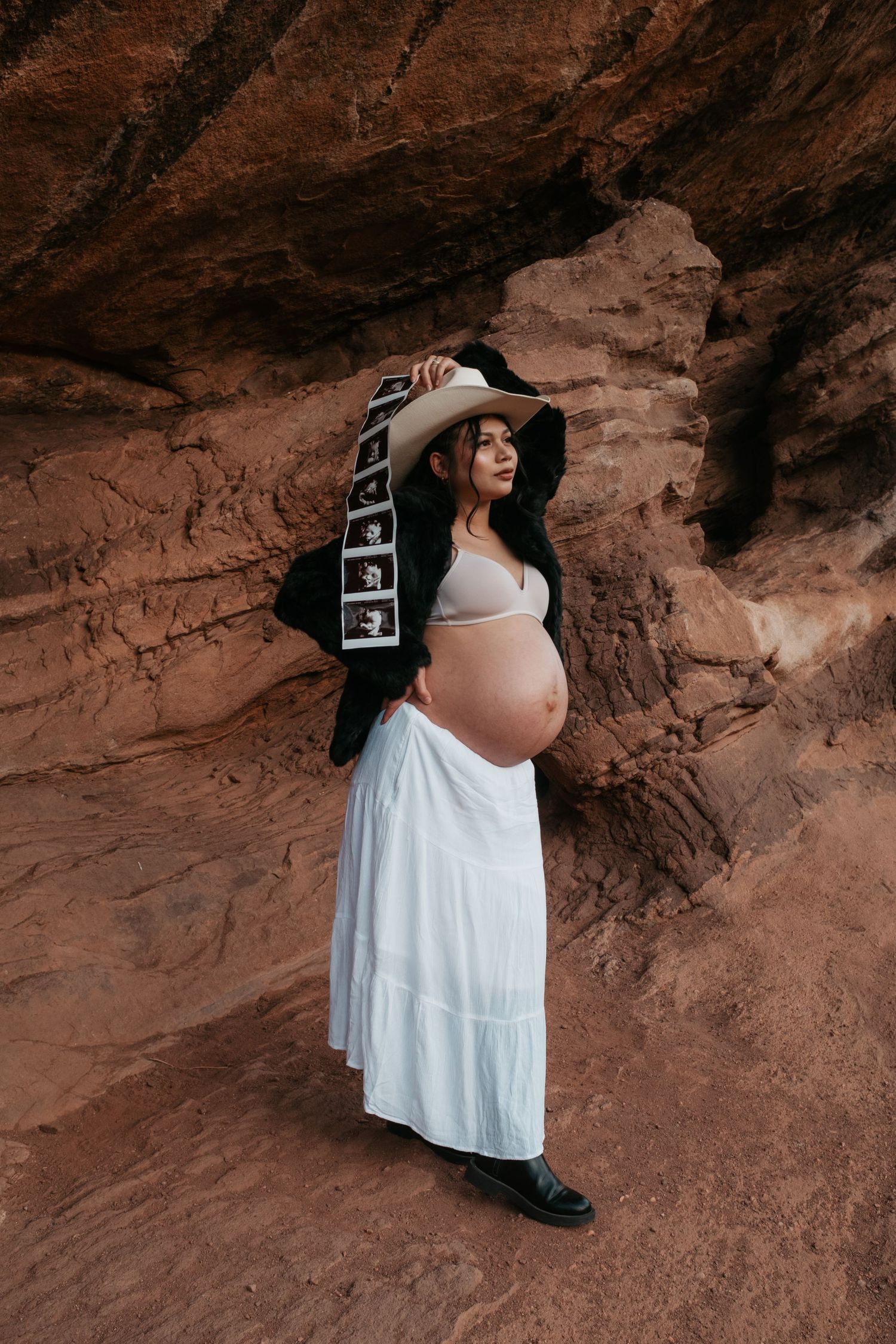 Artistic maternity photography session showcasing pregnancy silhouette against cave walls.