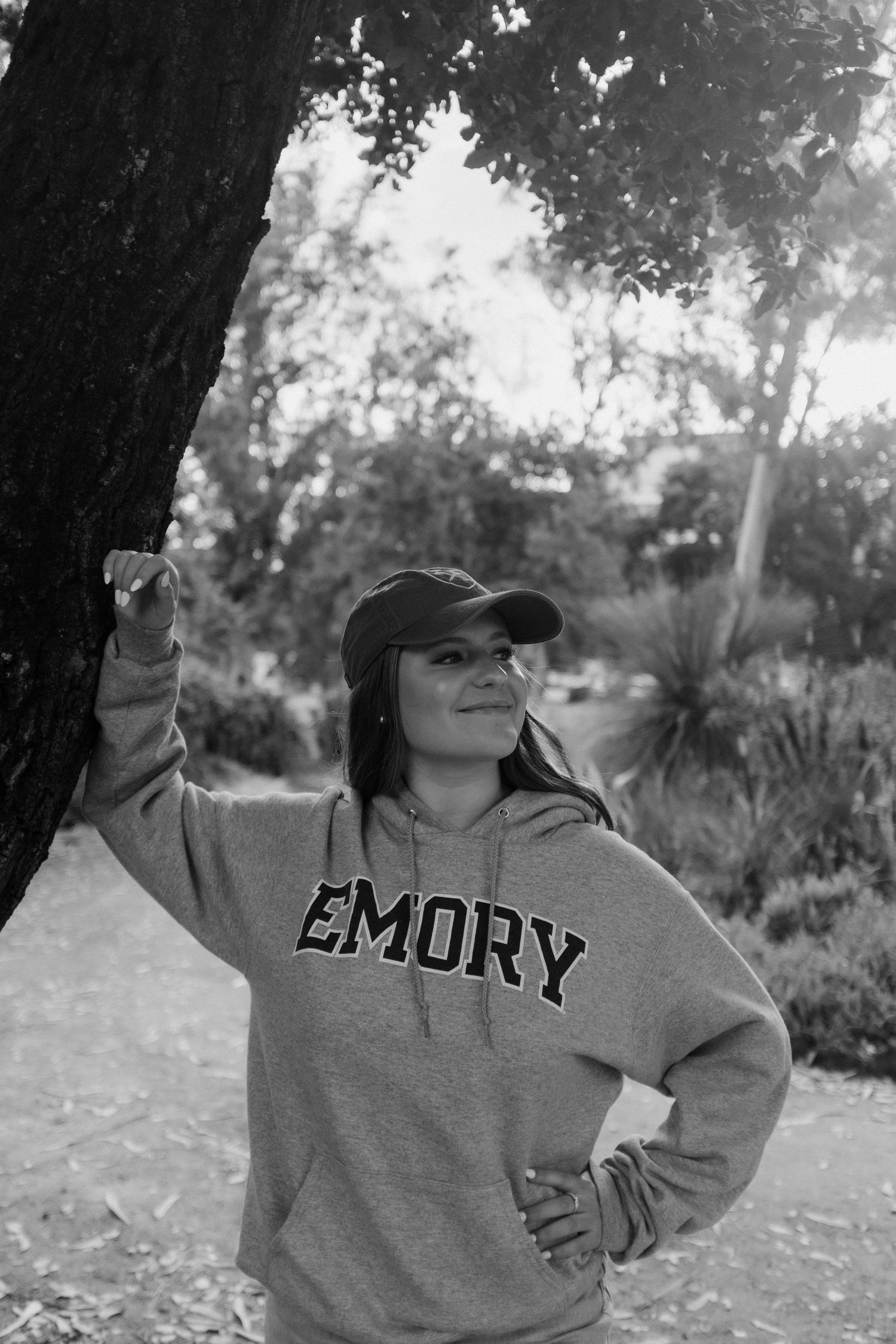A casual black and white portrait taken under a shady tree featuring an Emory sweatshirt.