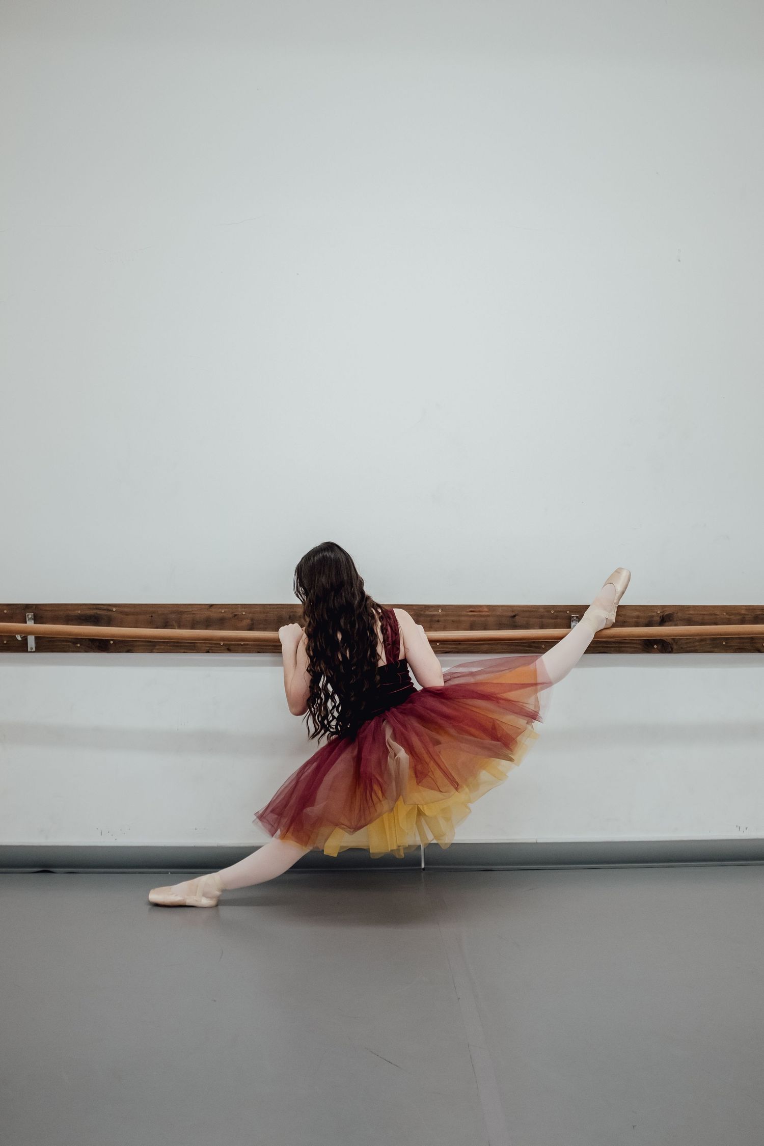 Dancer in tulle skirt performs floor sequence in dance studio.