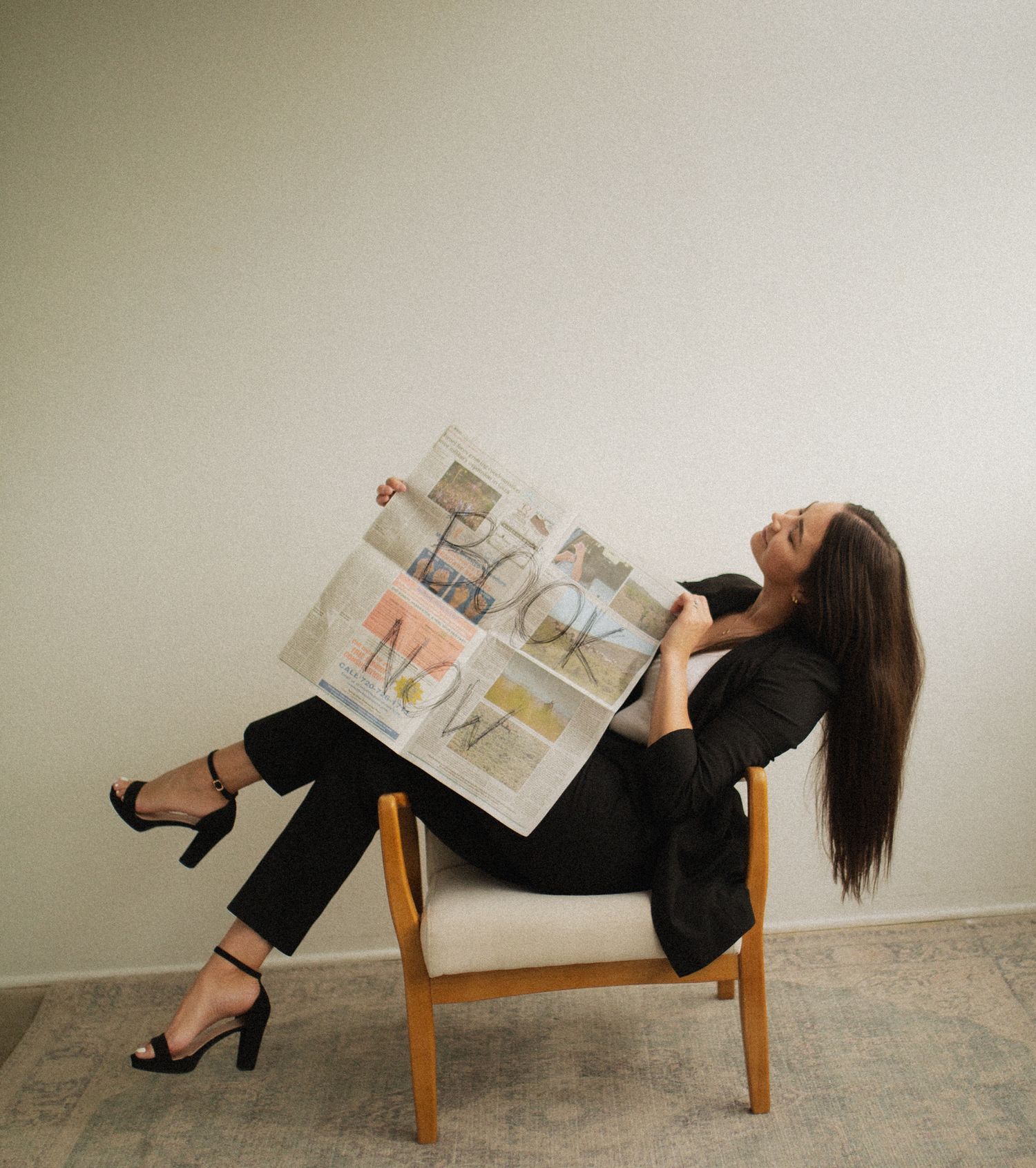 A person in black attire reclines on a wooden chair in multiple artistic poses against a minimalist backdrop.