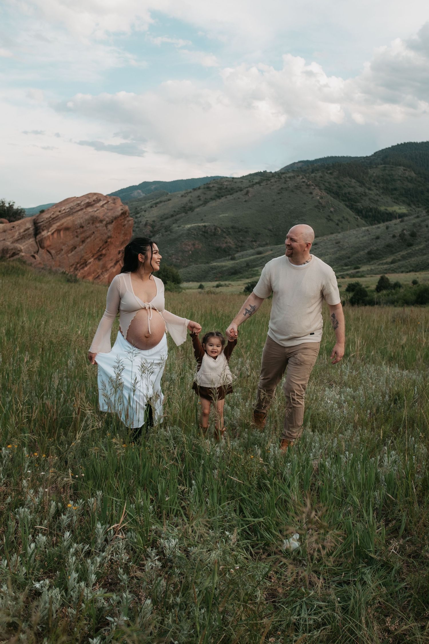 Family enjoying a candid moment together in wildflower field with mountain backdrop.