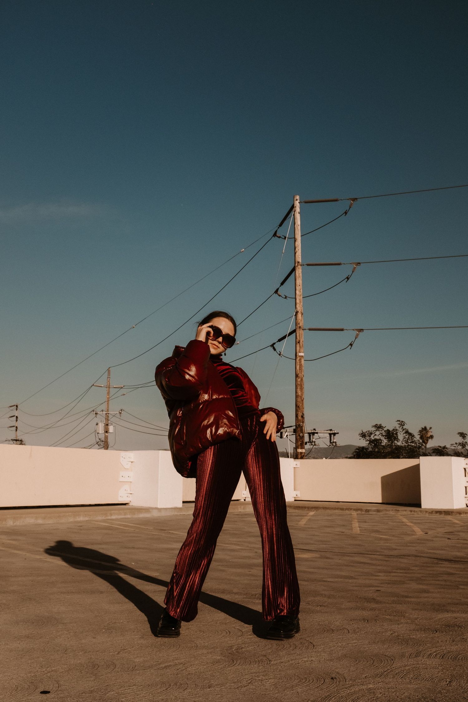 Person in red velvet suit poses confidently on rooftop with power lines in background.