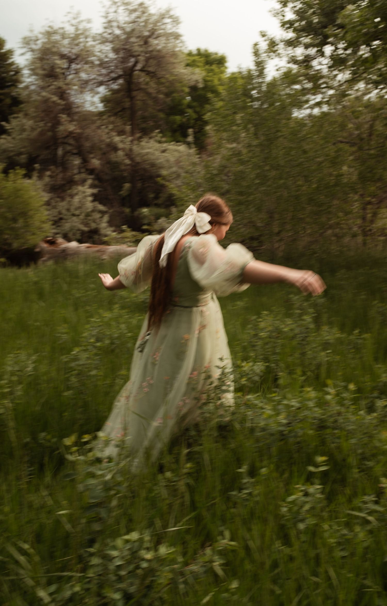 Person spinning in flowy mint dress amid wild spring meadow.