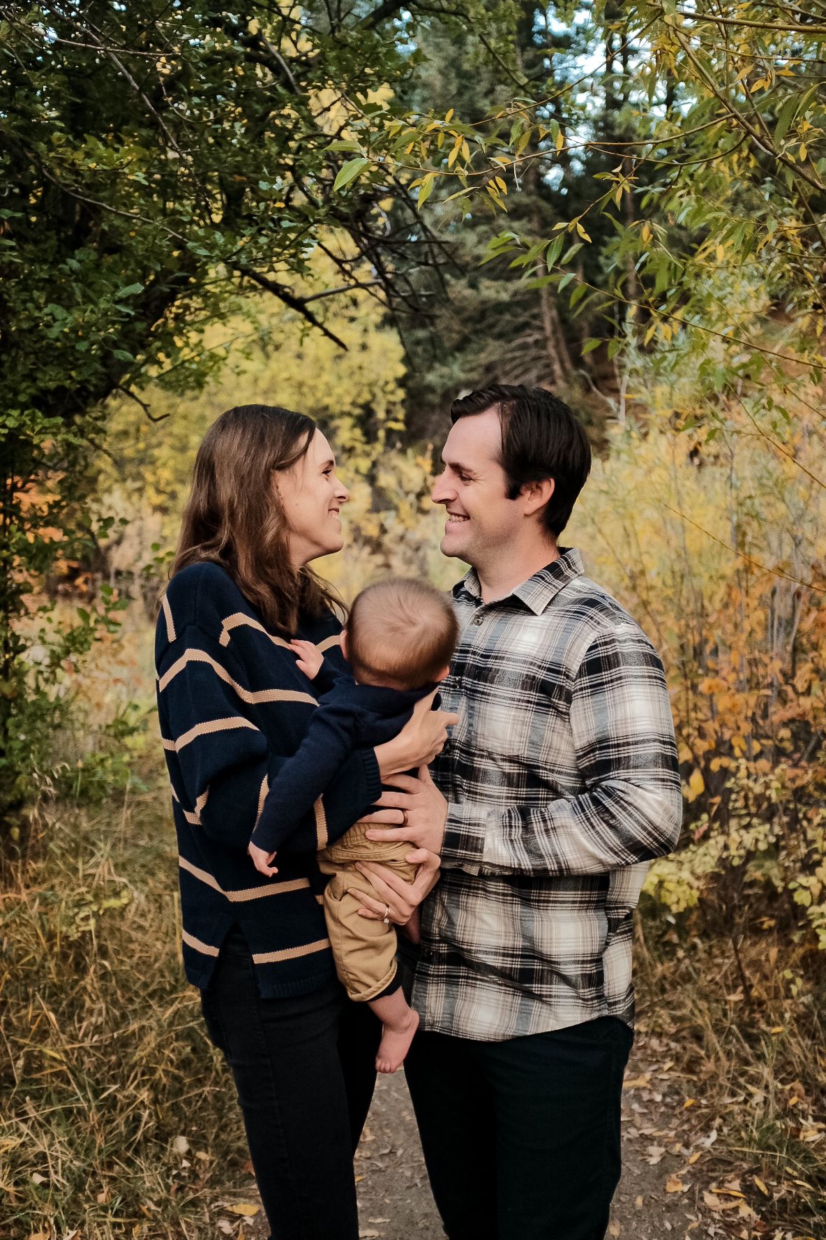 Loving family moment captured in autumn foliage on a nature path.