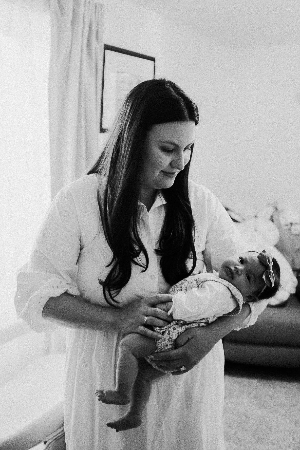 Intimate black and white photo of a tender moment between parent and newborn.