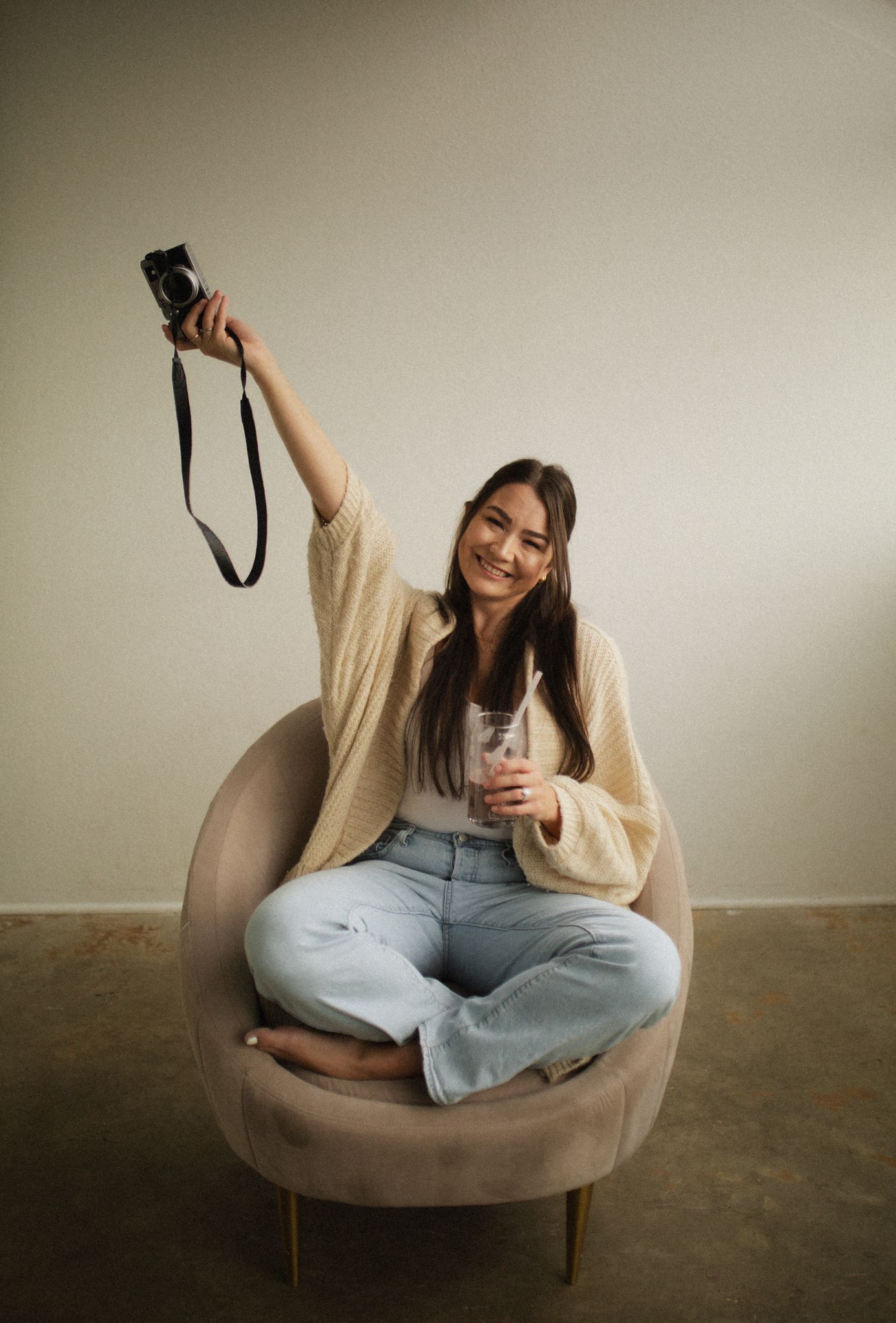 Person sitting in a cozy beige armchair wearing casual attire shows different relaxed poses against neutral wall.