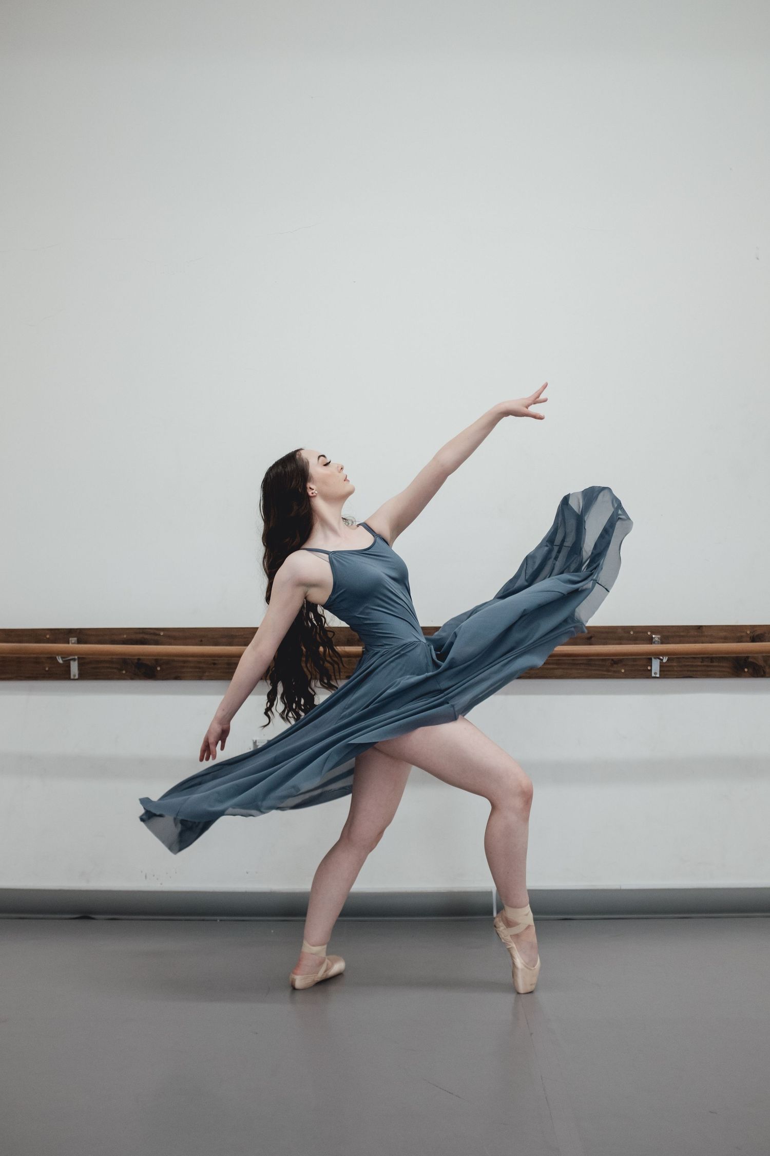Dancer in blue dress performs expressive movements with flowing fabric.