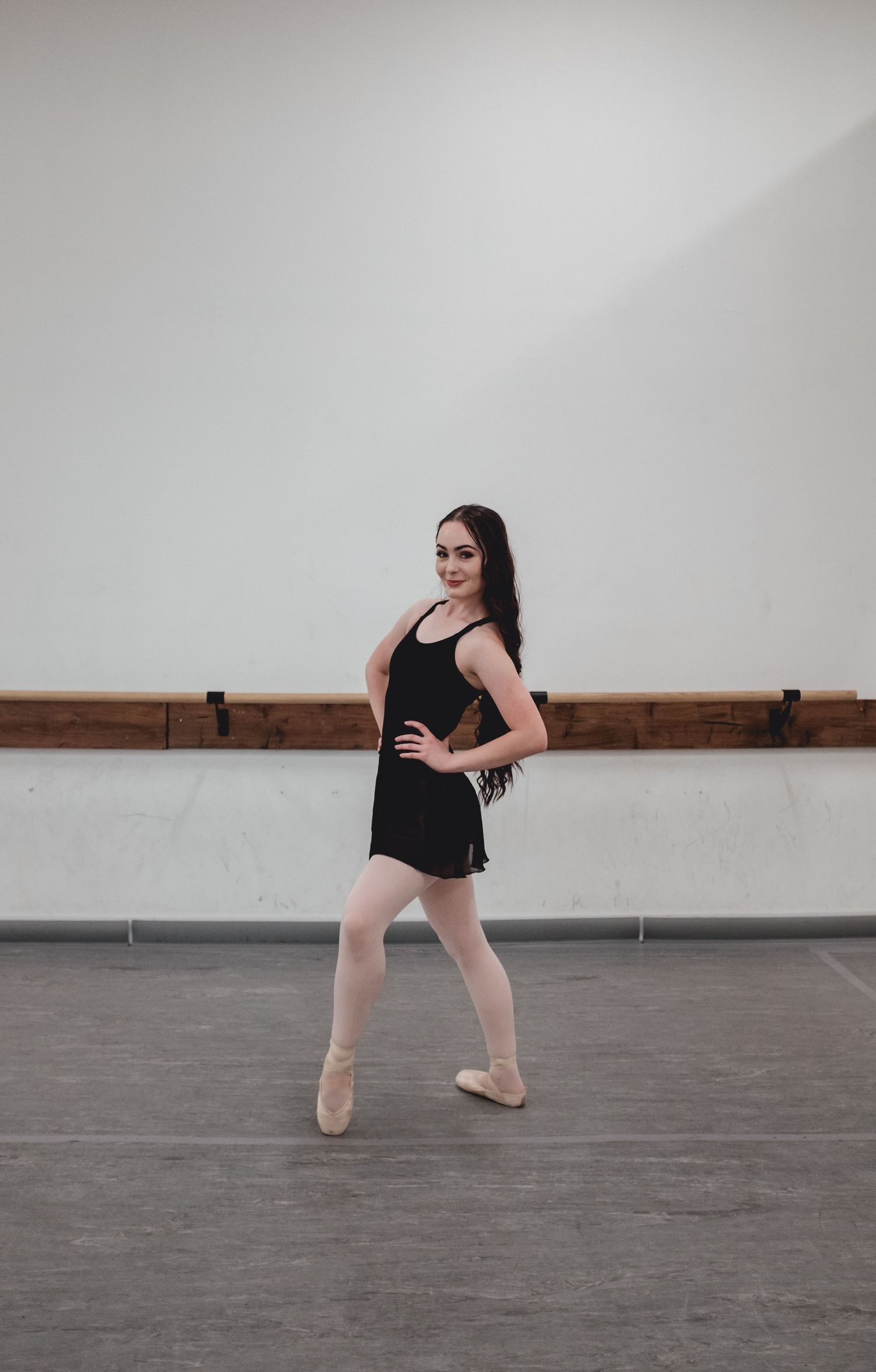 Contemporary dancer performs dynamic movement sequence in minimalist studio space.