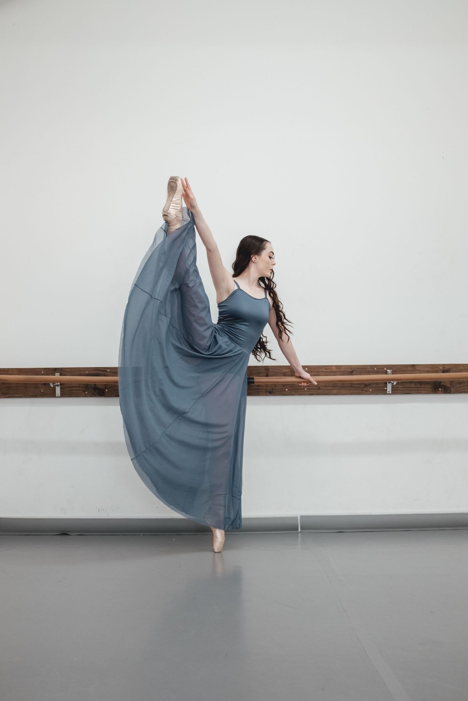 Dancer in flowing blue dress creates elegant shapes during studio performance.