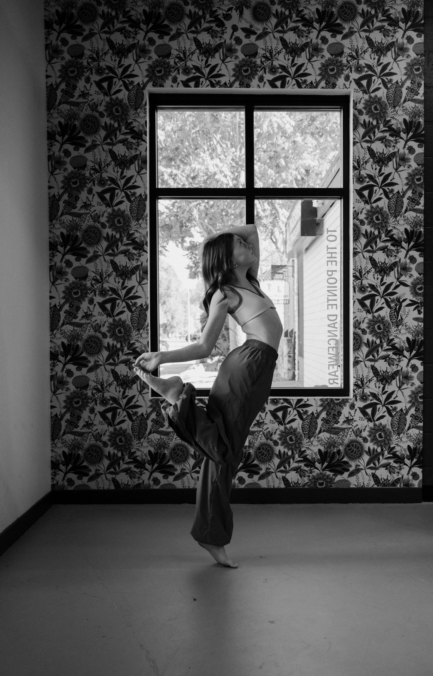 A sequence of black and white photos showing a figure climbing through a window with floral wallpaper in the background.